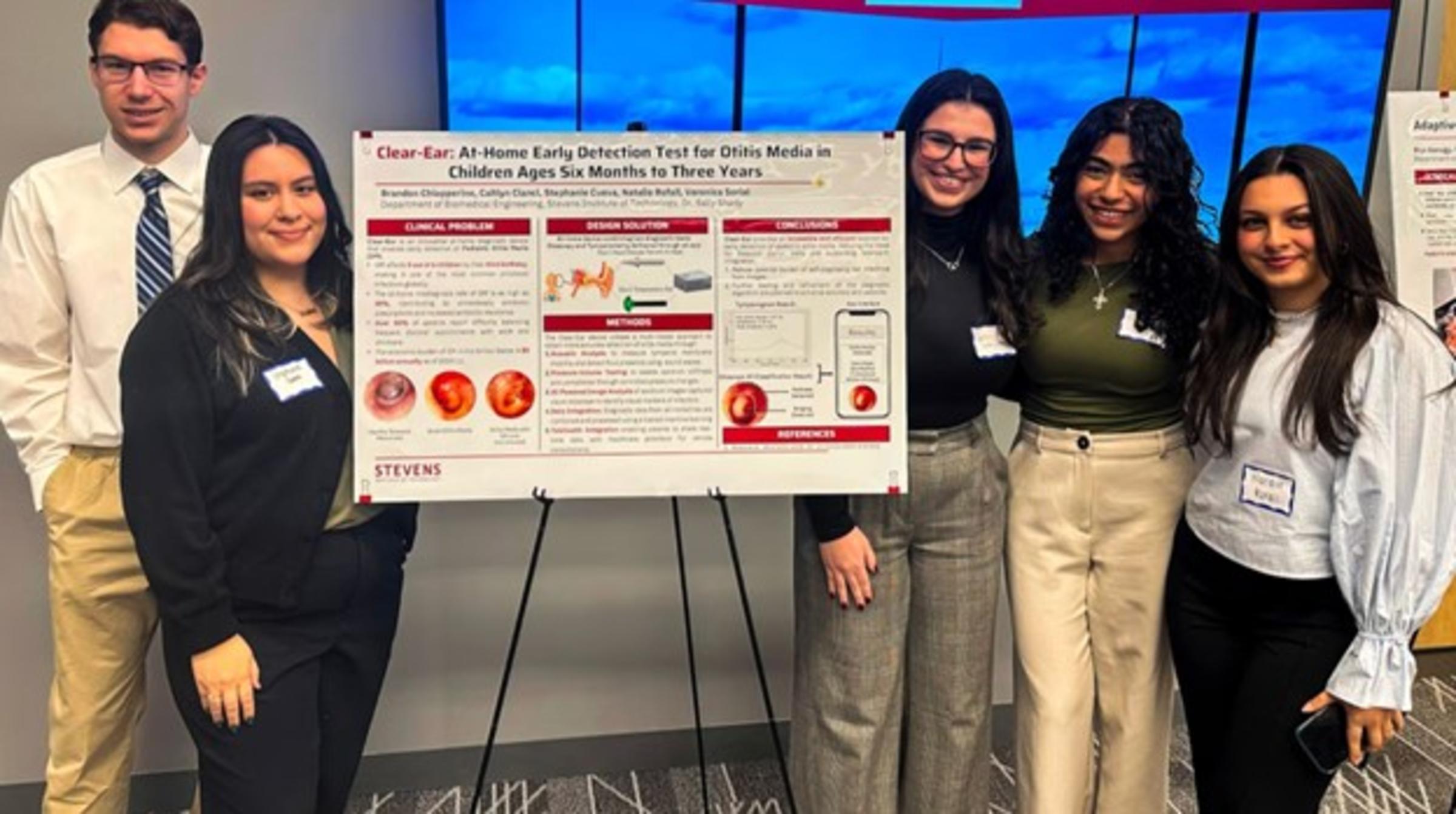 A group of 5 students stand around a poster presentation.