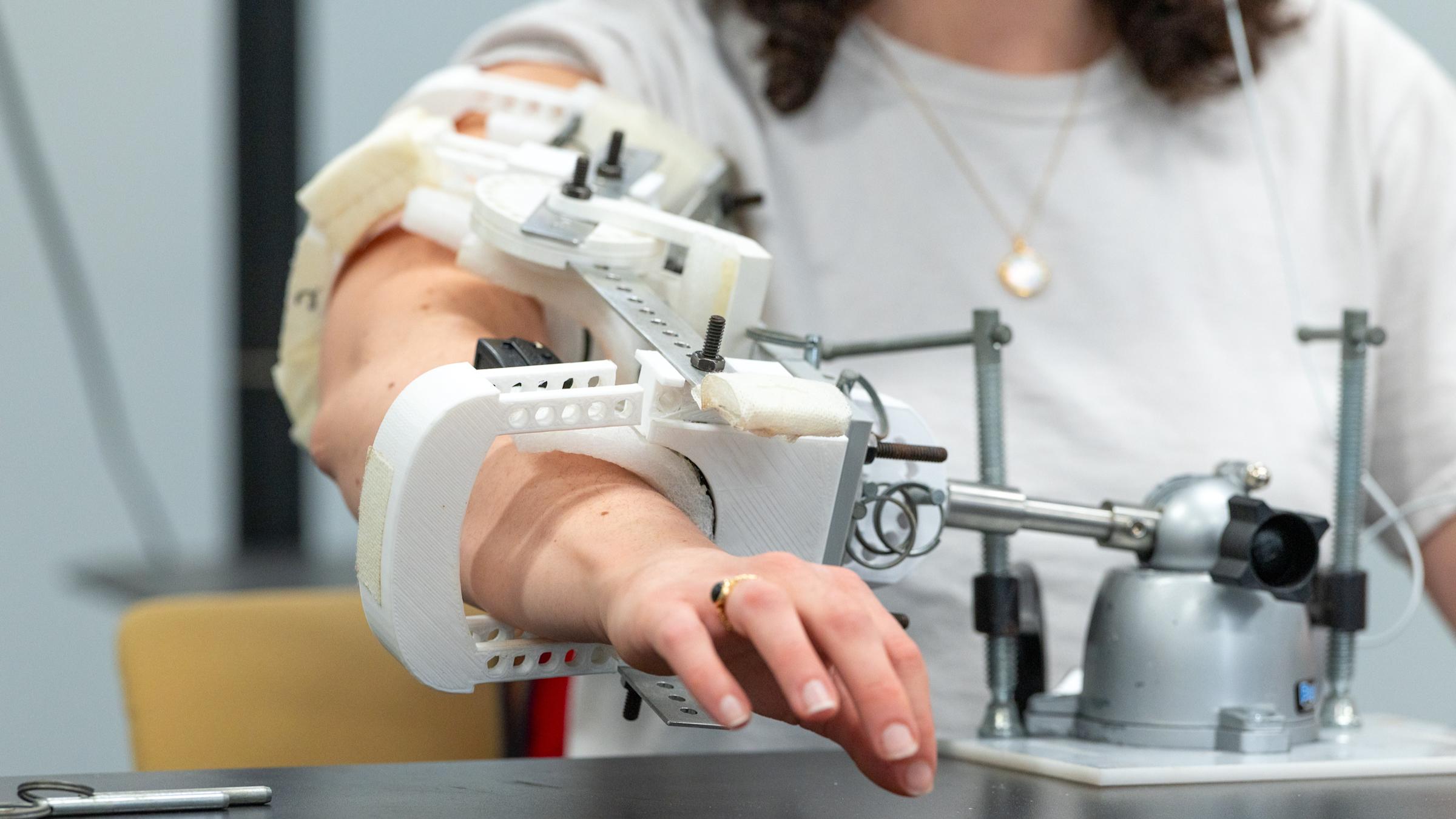 A test subject wearing a wired plastic and metal engineering sleeve on the arm.