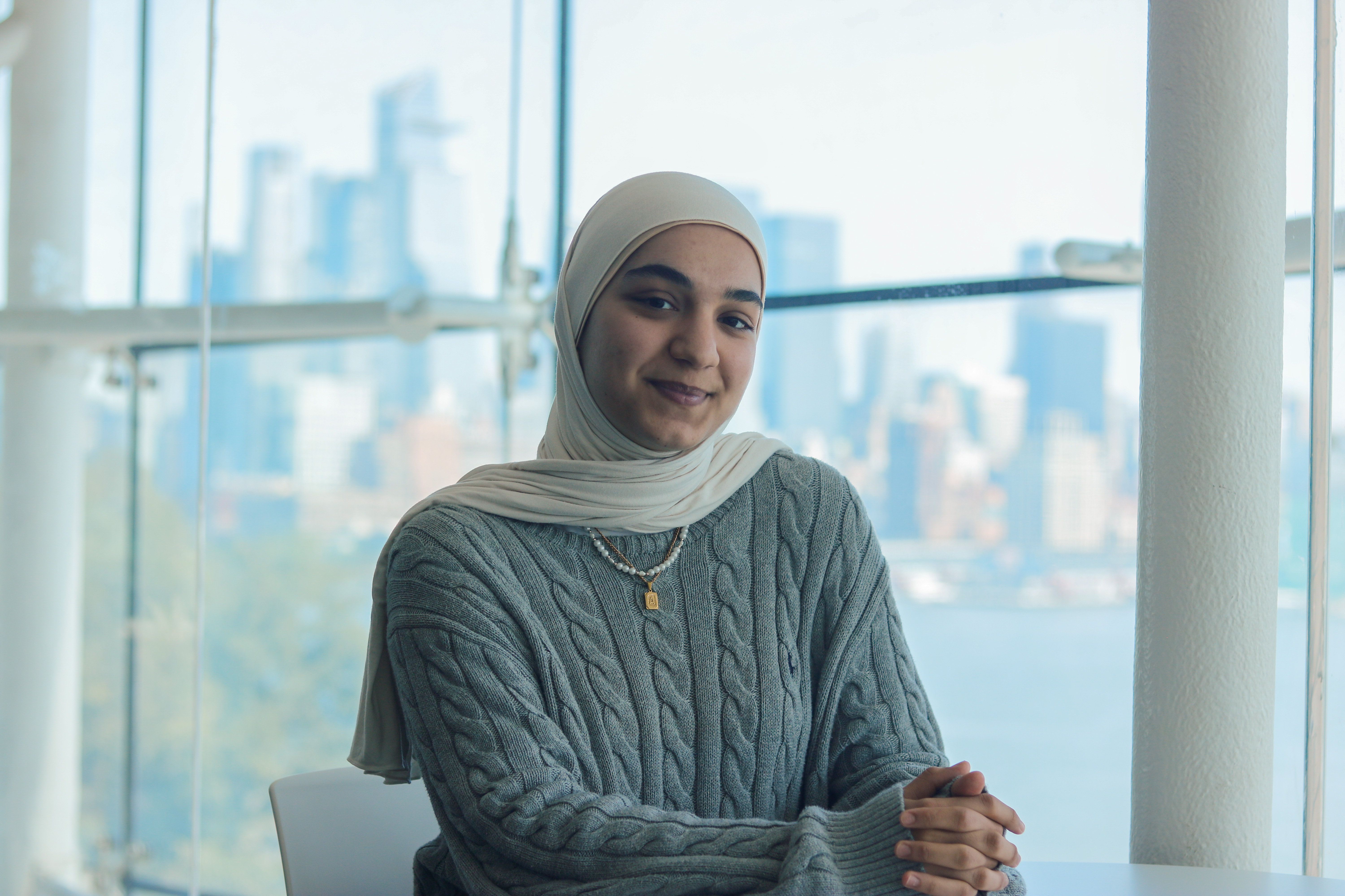 Aylin Erdal sits in the Babbio Lounge with some of the New York City skyline behind her