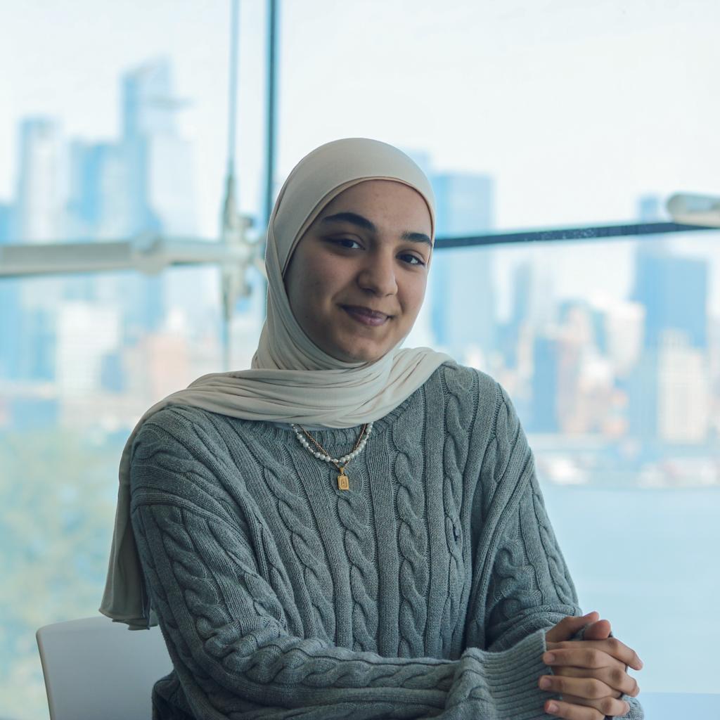Aylin Erdal sits in the Babbio Lounge with some of the New York City skyline behind her