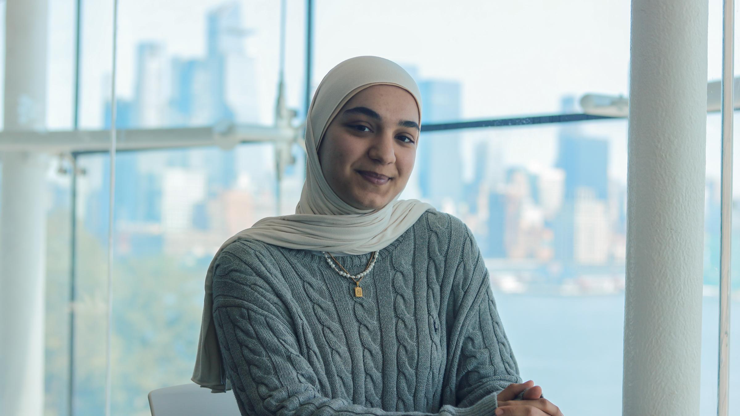 Aylin Erdal sits in the Babbio Lounge with some of the New York City skyline behind her