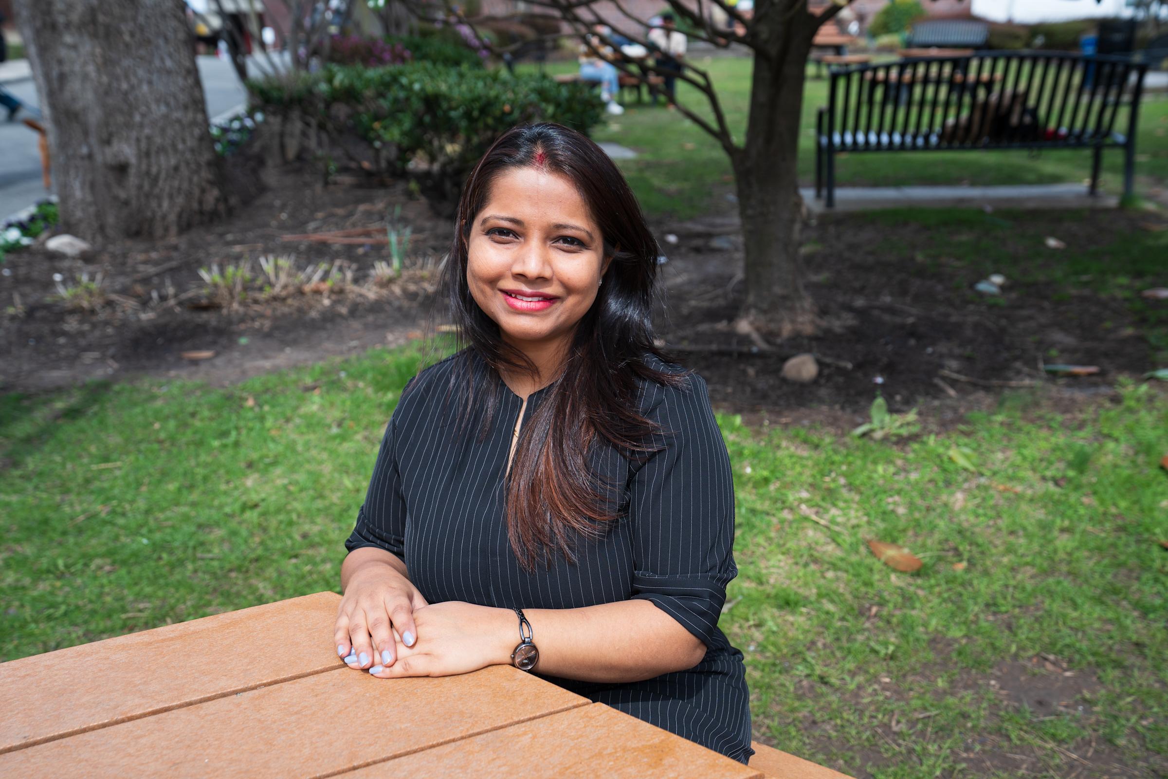 Diksha Kishore sits at a small picnic table in a garden on the Stevens campus.