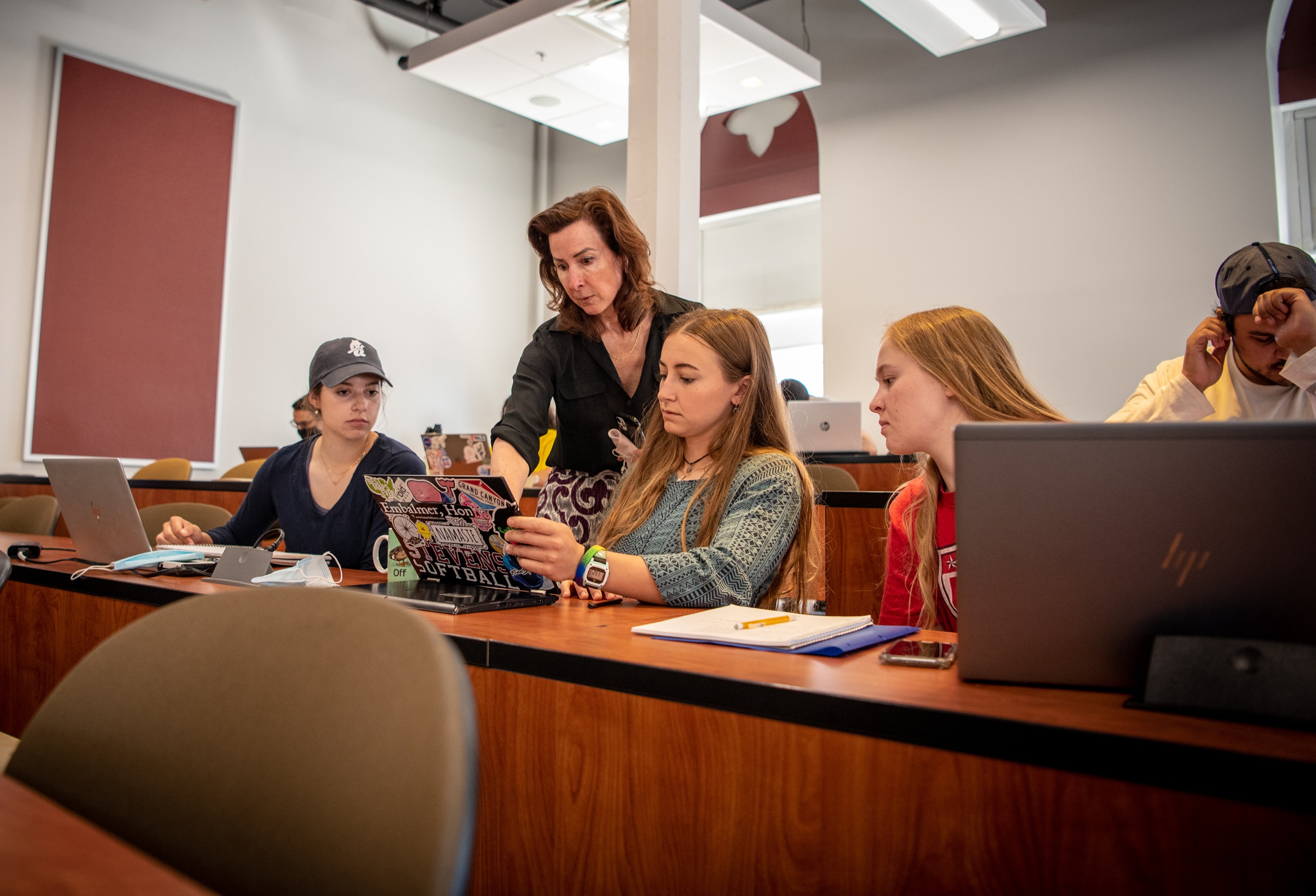 Three female students and a male student in a classroom with their female professor