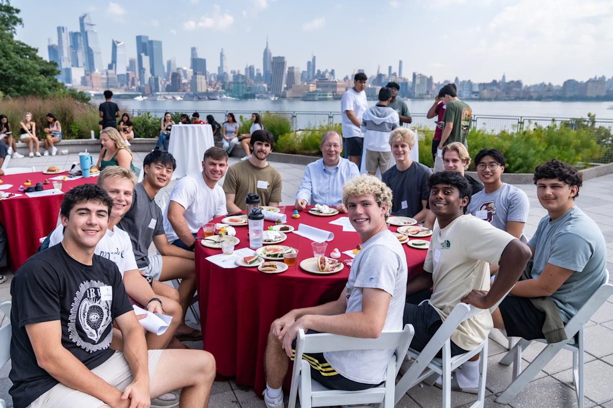 GJ de Vreede poses for a photo with a table full of students.