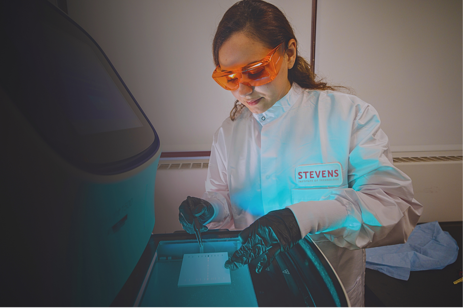 A student with goggles and a medicine dropper carefully operating lab equipment.
