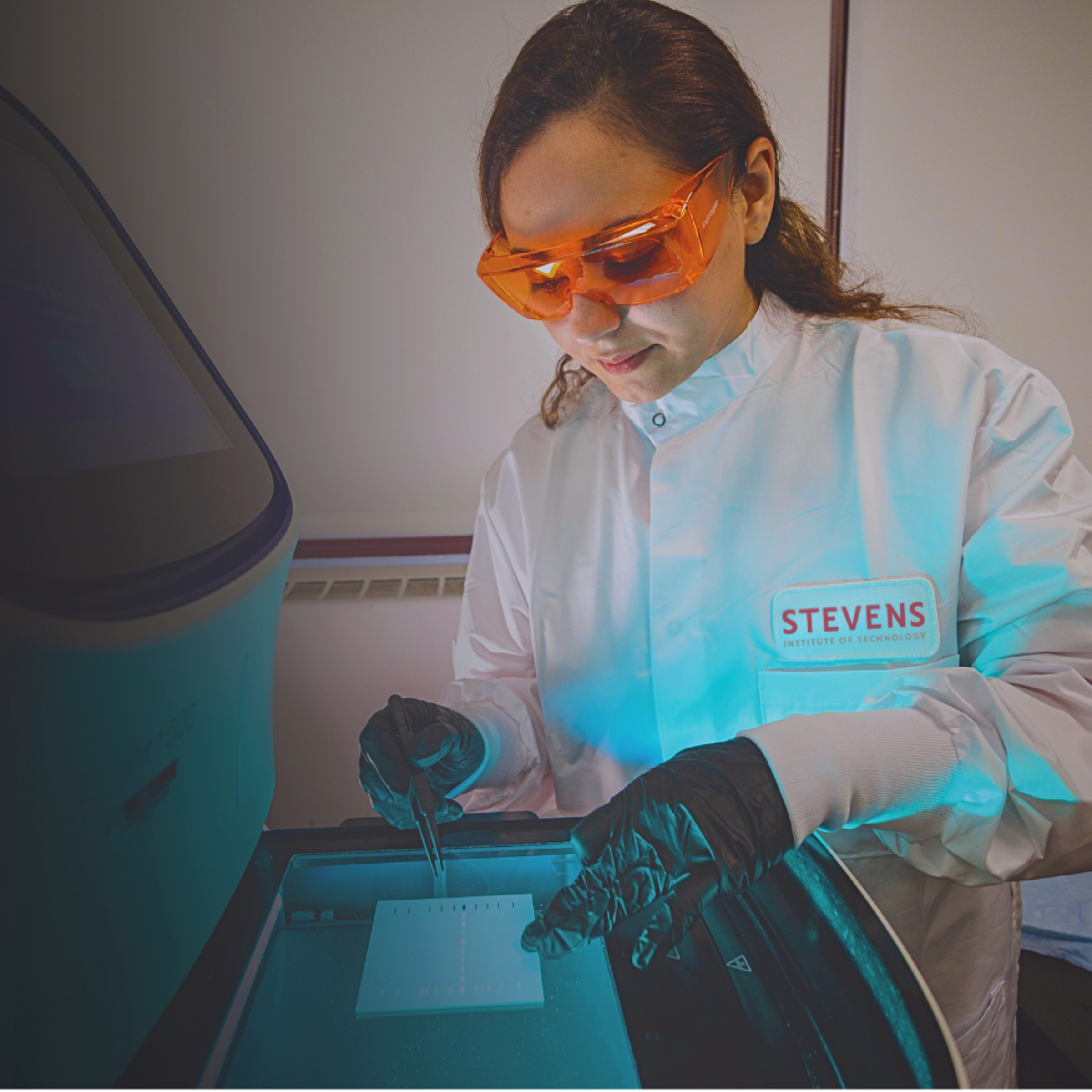 A student with goggles and a medicine dropper carefully operating lab equipment.