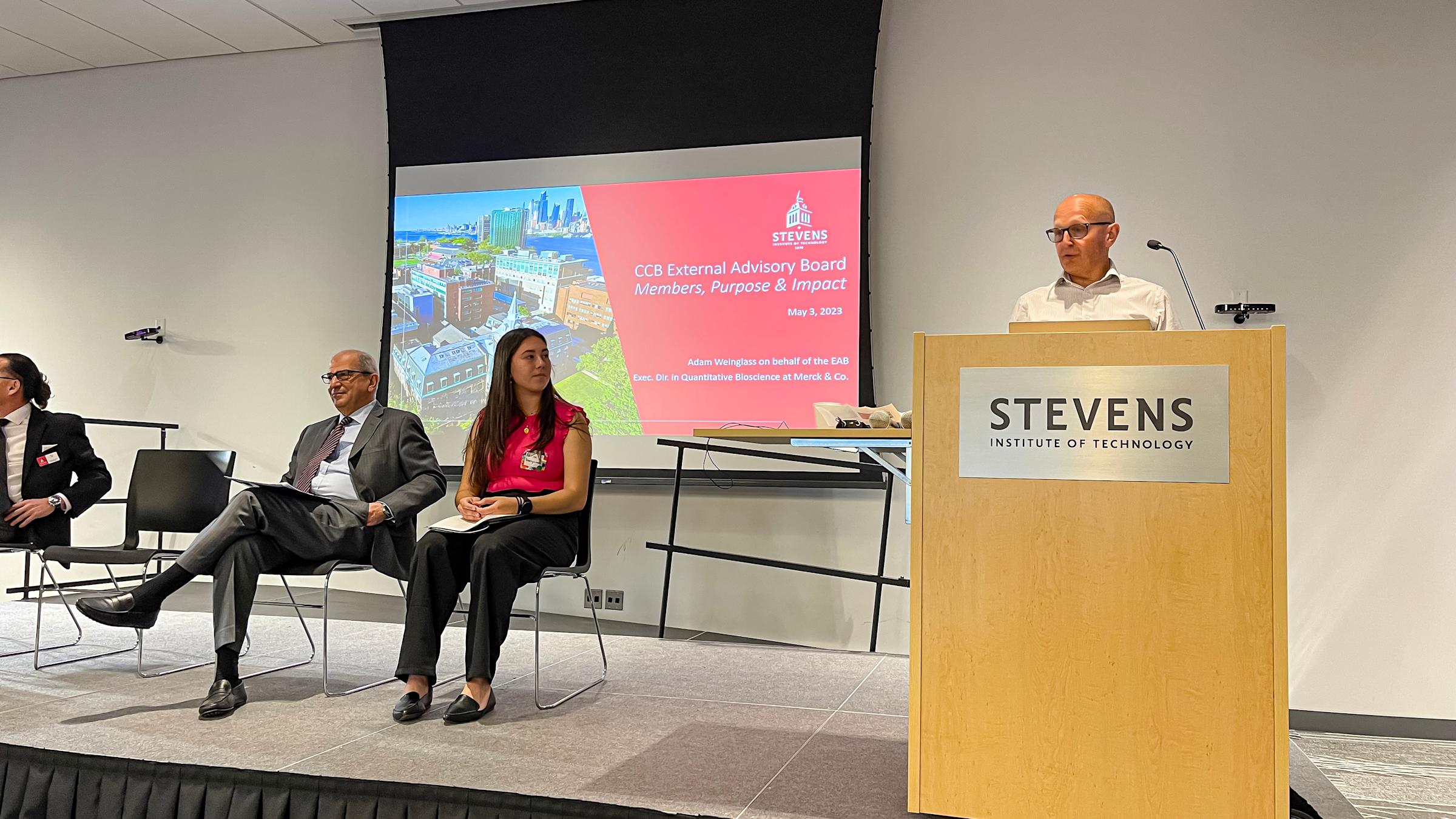 Executive Advisory Board member Adam Weinglass speaks at a podium.