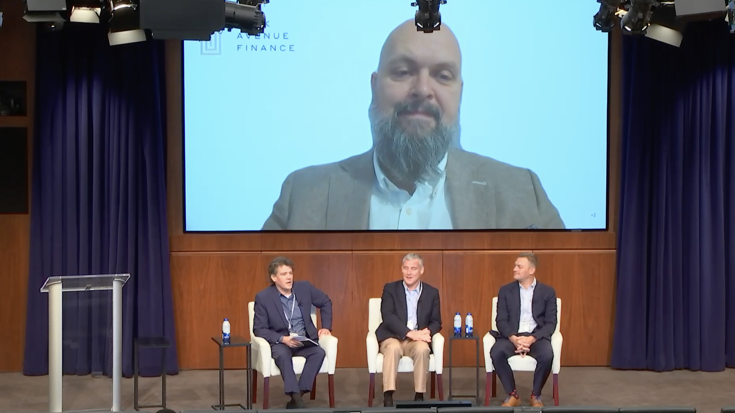 The members of the panel sit on the stage speaking with the audience.