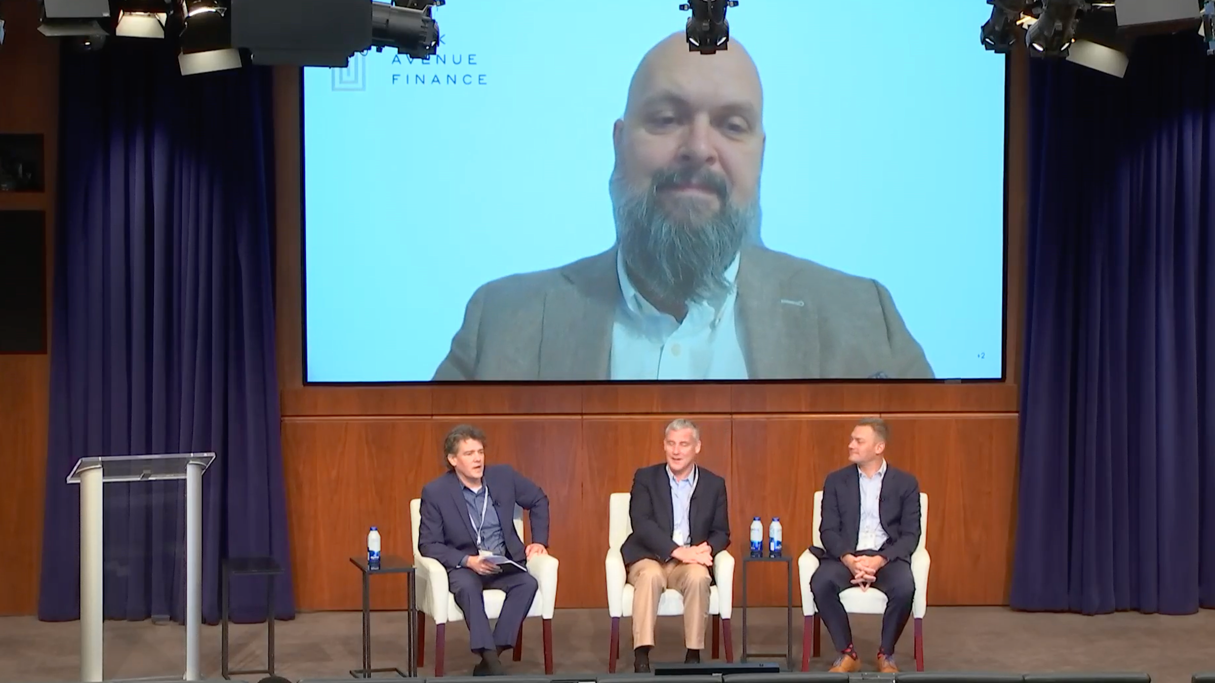 The members of the panel sit on the stage speaking with the audience.