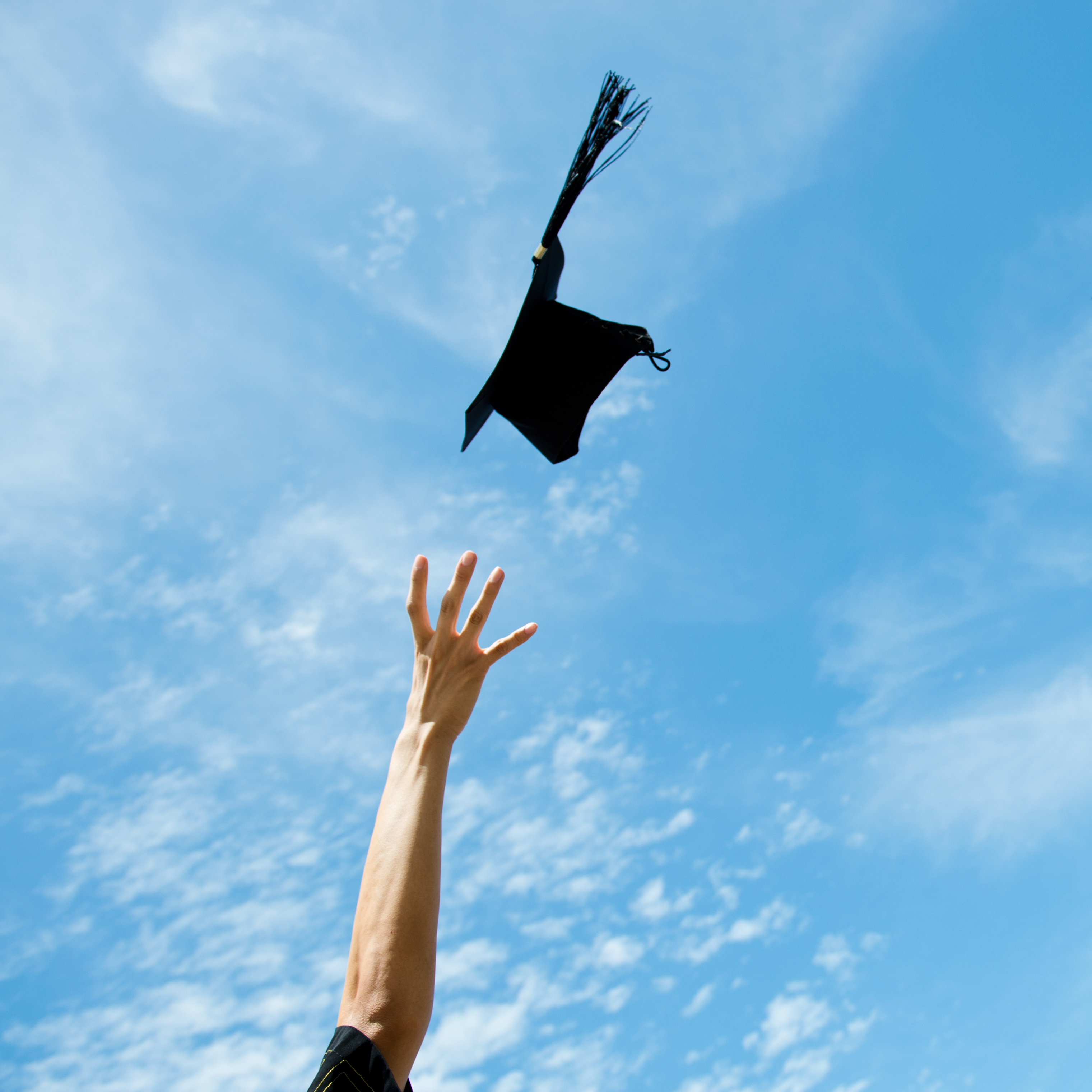 Photo of arm throwing graduation cap in the air