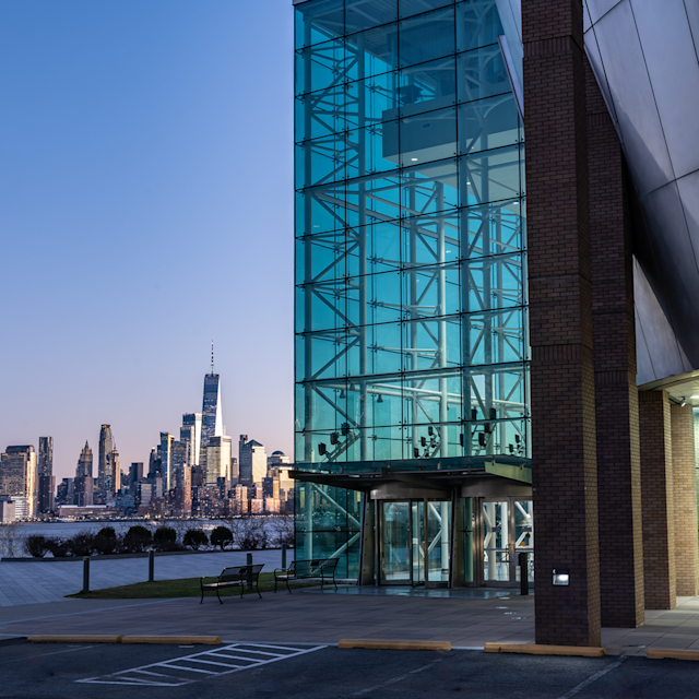 The Babbio Center with part of the New York City skyline in the background at dusk