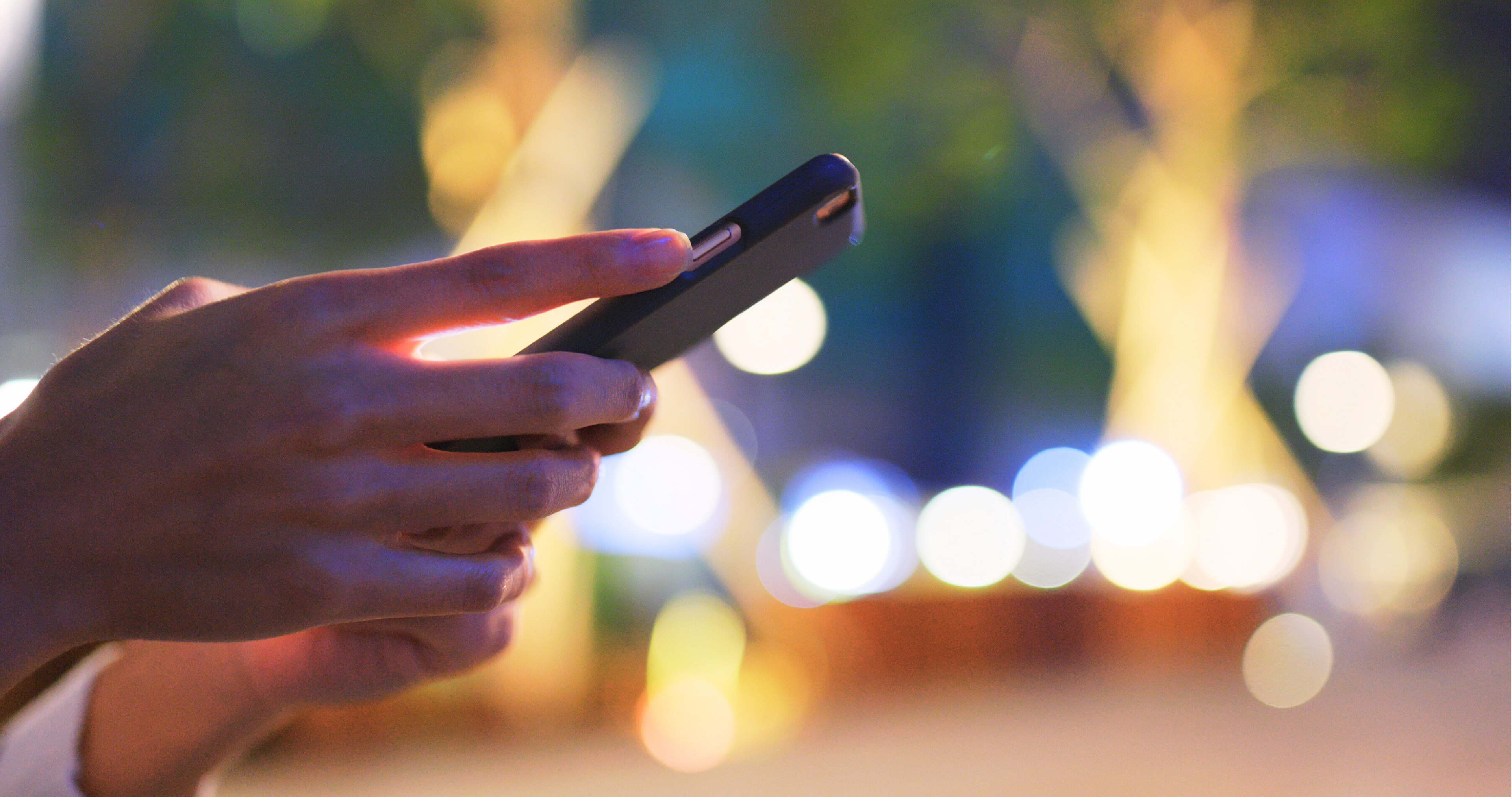 A person's hands holding a RF-sensing wireless device in a city scape.