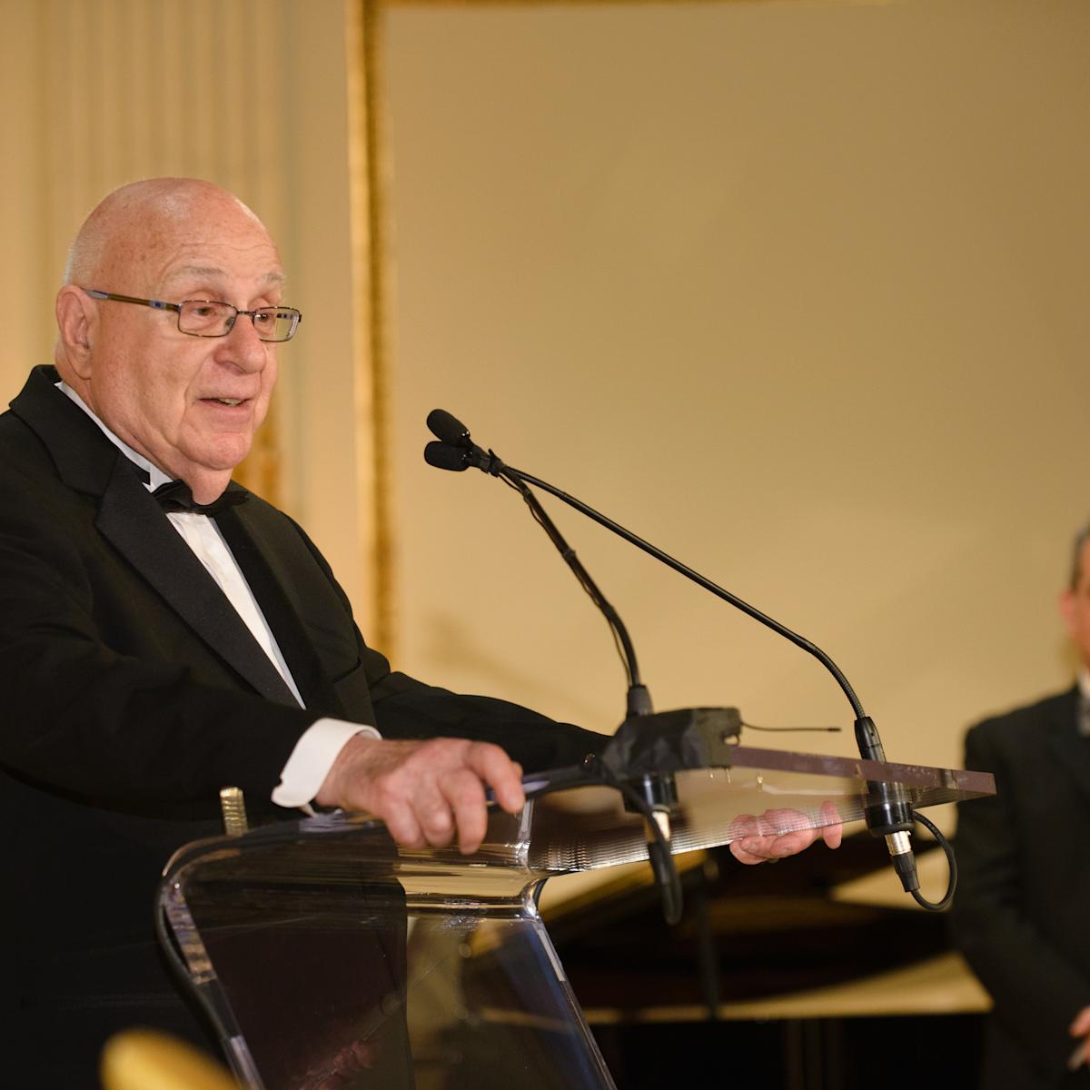 A man speaks into a microphone behind a podium.