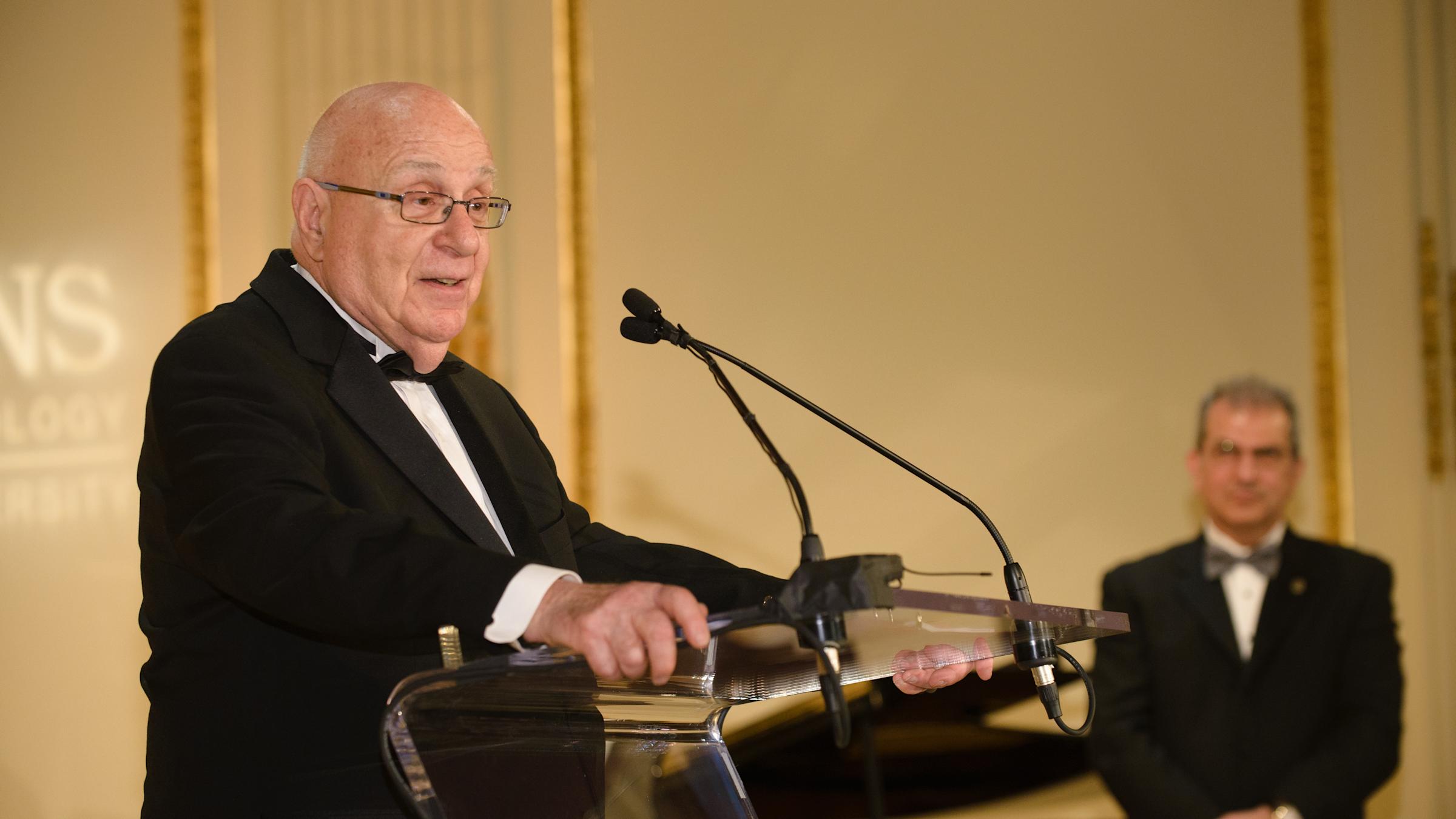 A man speaks into a microphone behind a podium.