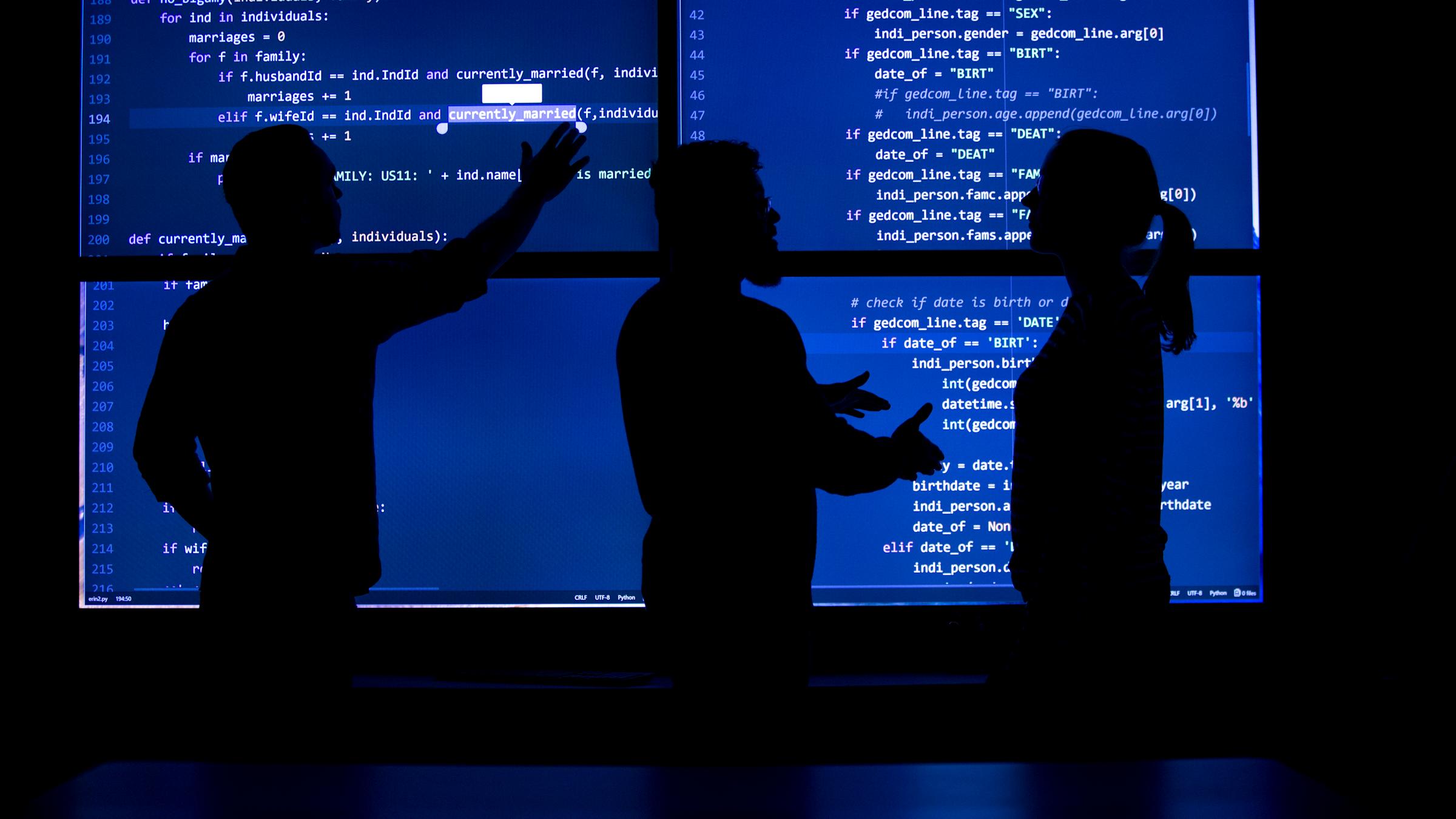 Three students silhouettes on 4 large, blue, computer screens