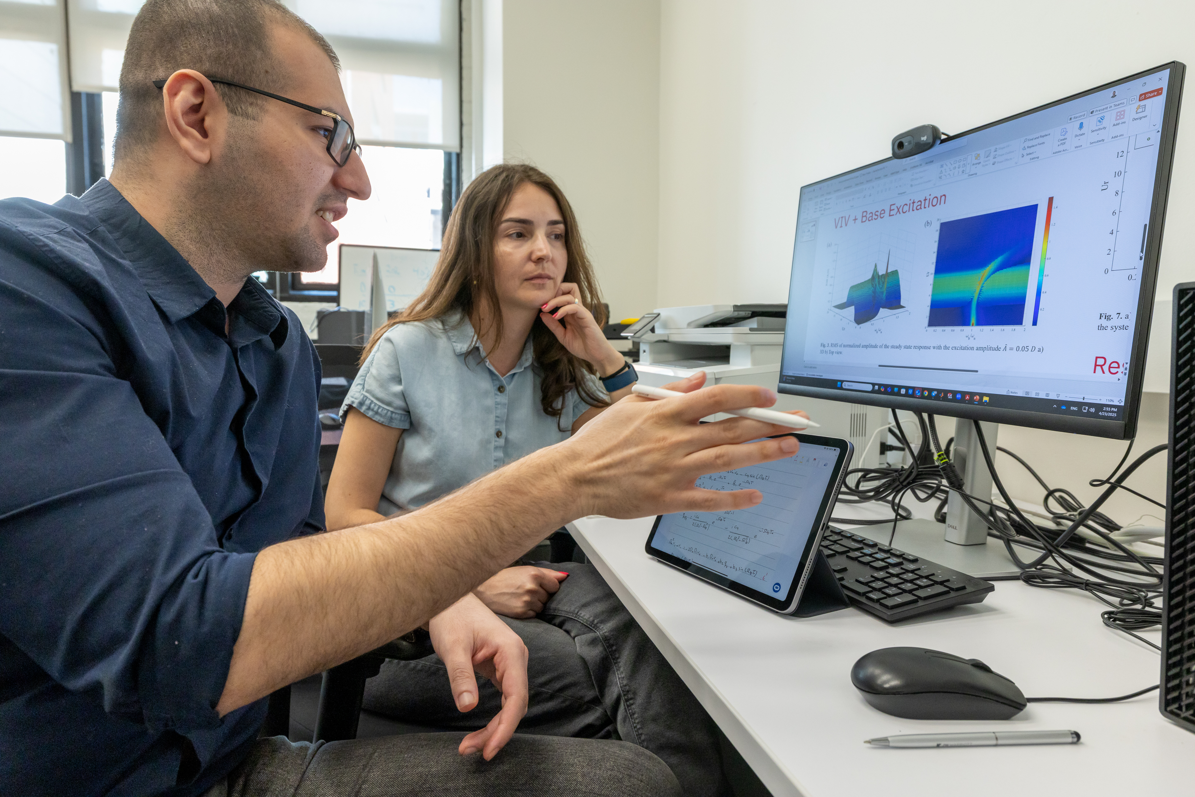 A student converses with the professor about information on a computer screen.