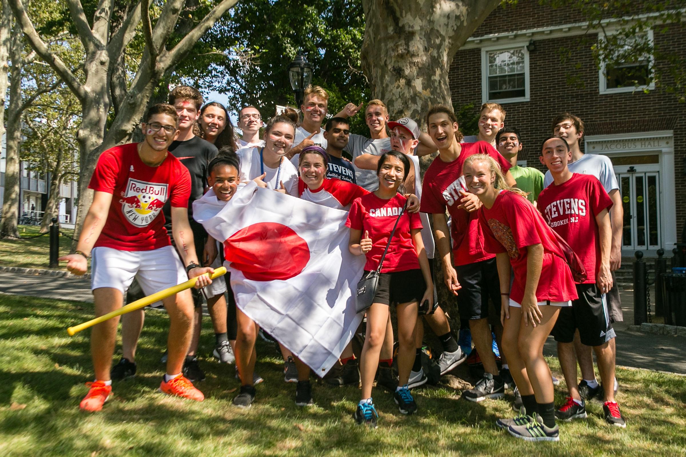 Group of students wearing red and holding a Japan flag outside