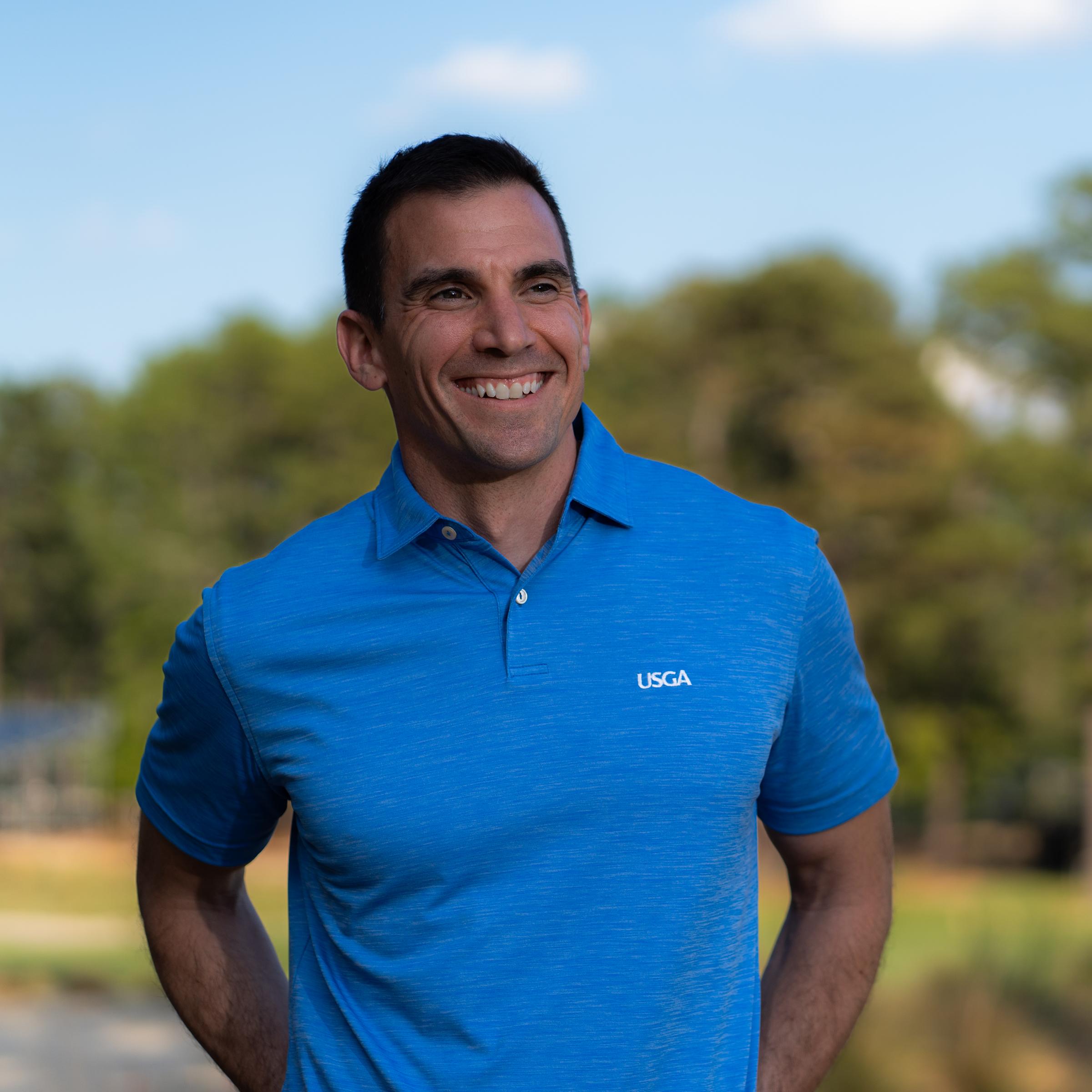 Anthony Santora M.S. ’05 headshot outside wearing a blue USGA shirt