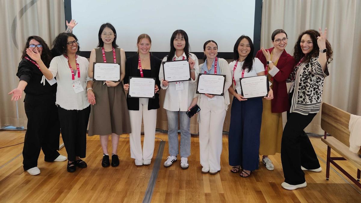 Ivana Collado Gonzalez (fourth woman from the right) holding an award certificate in her hand, smiling at the camera.