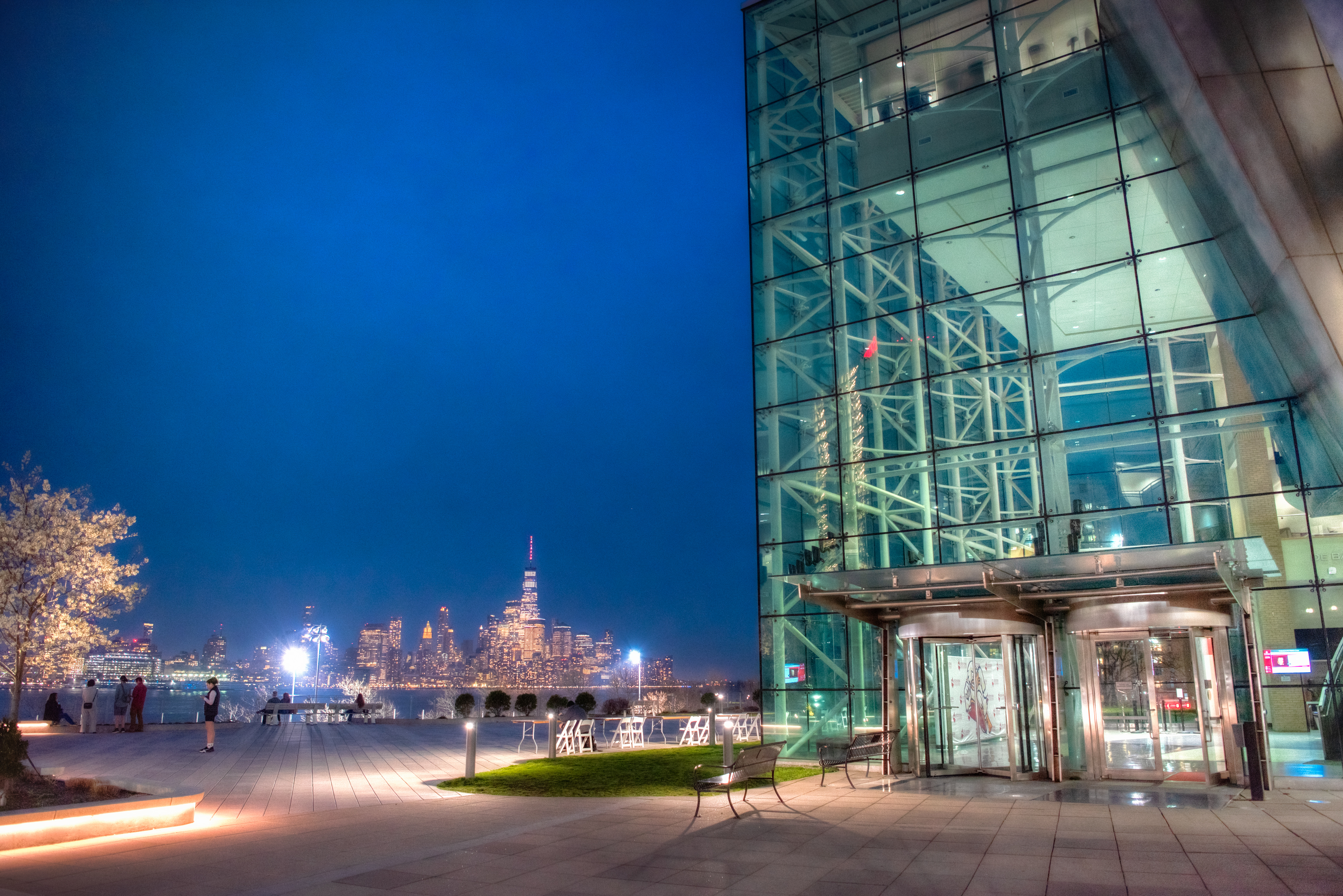 Babbio Center on Stevens campus lit up at night with New York City in background.