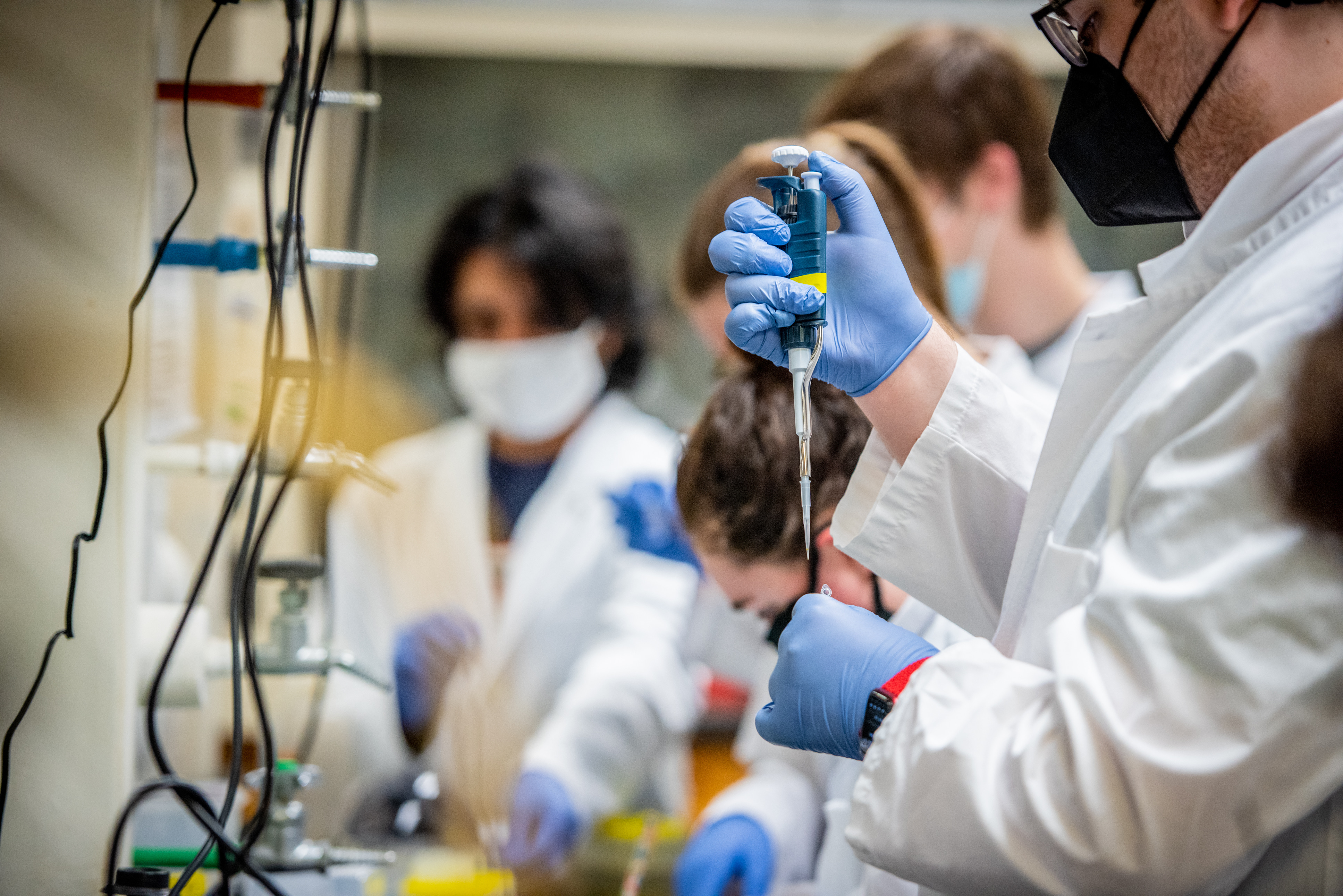 Male and female students working in a lab with a syringe. 