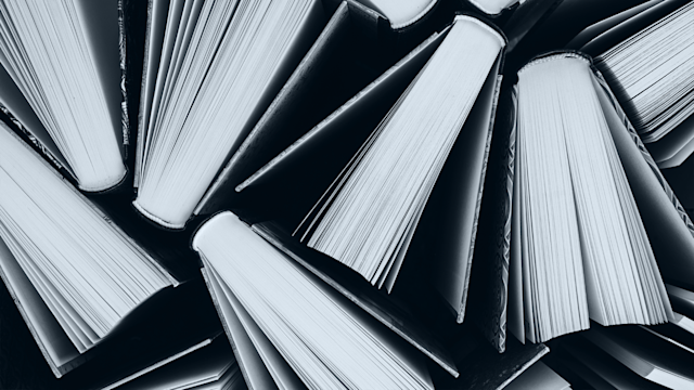 Books from above. Black and white image with light blue overlay.