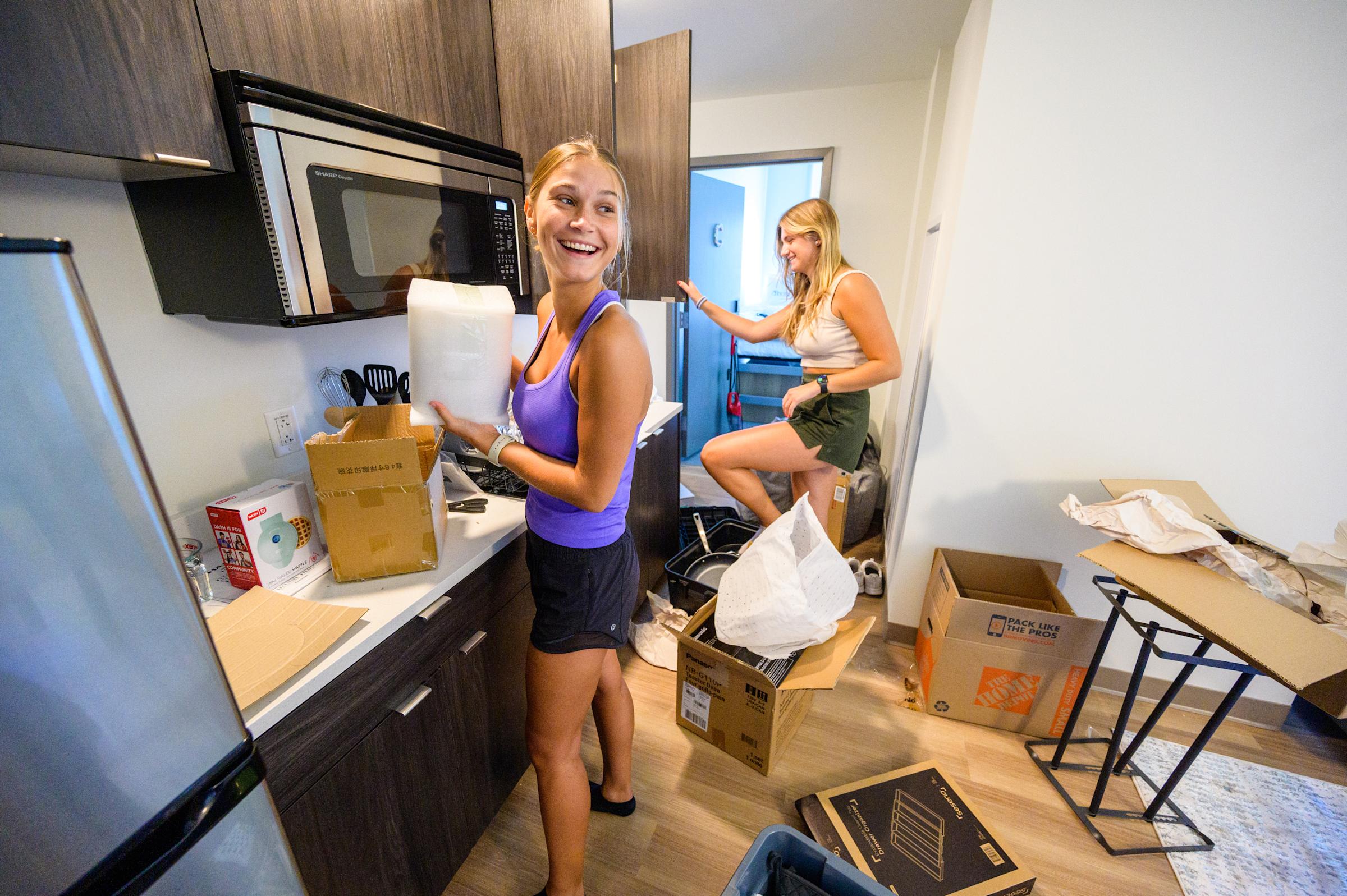 Students smaile as they unpack into their kitchen.