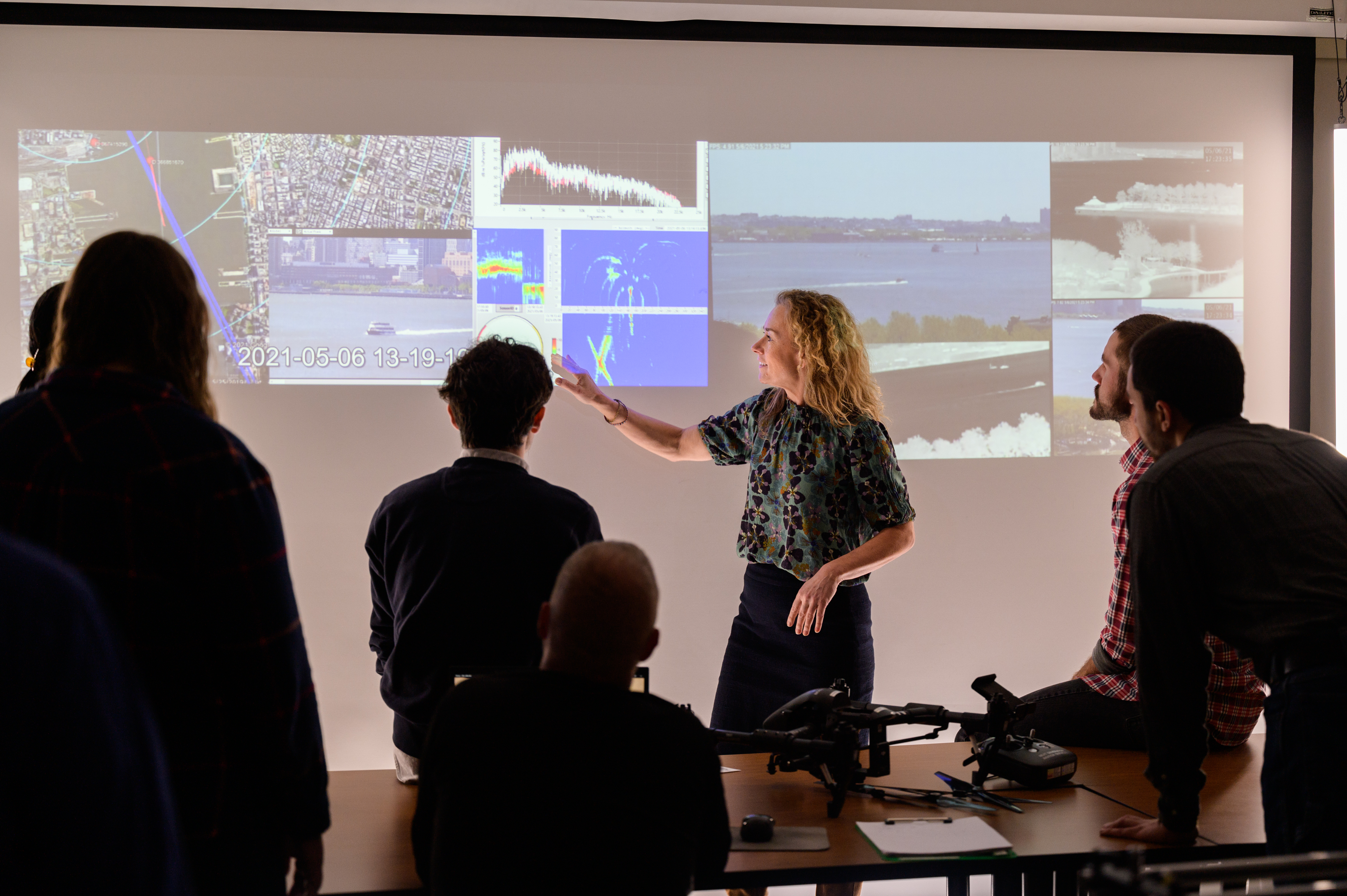 Intructor gestures to projected images of port security in class.