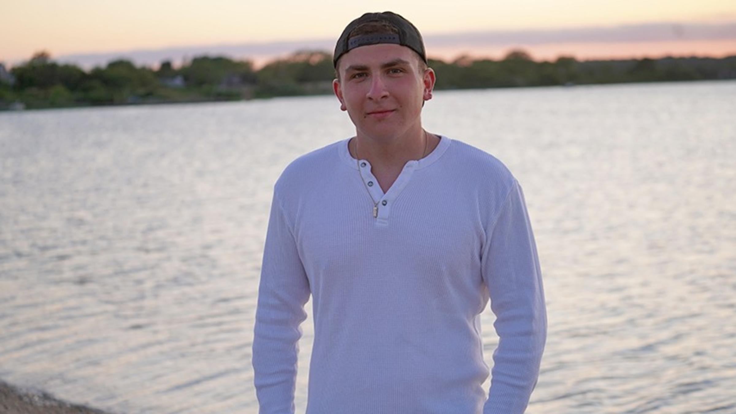 Jesse Kay outdoors by a shoreline at sunset.