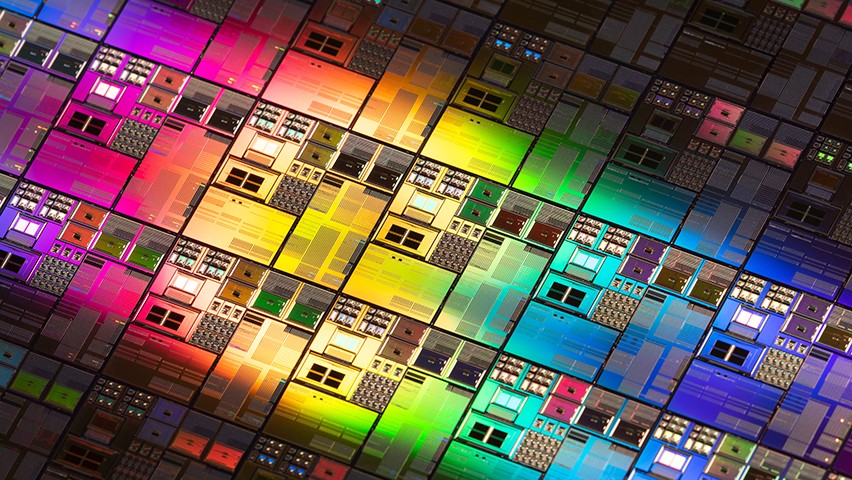 A close-up studio photo of rainbow-colored iridescent silicon computer wafers. Chips like these are increasingly designed through artificial intelligence.