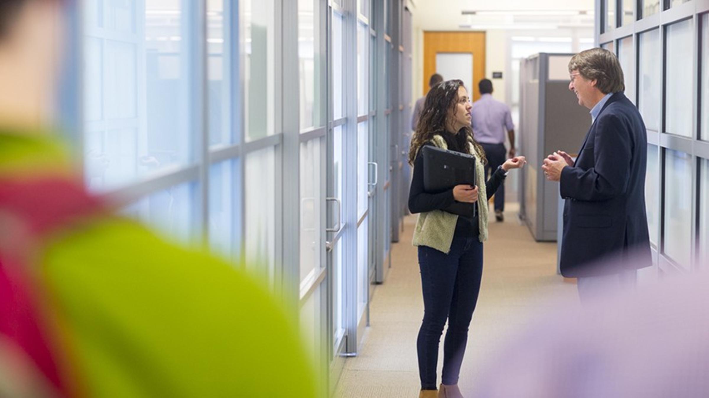 Katti Thomasian and Dr. Kevin Ryan speak in a crowded corridor in the Babbio Center at Stevens.