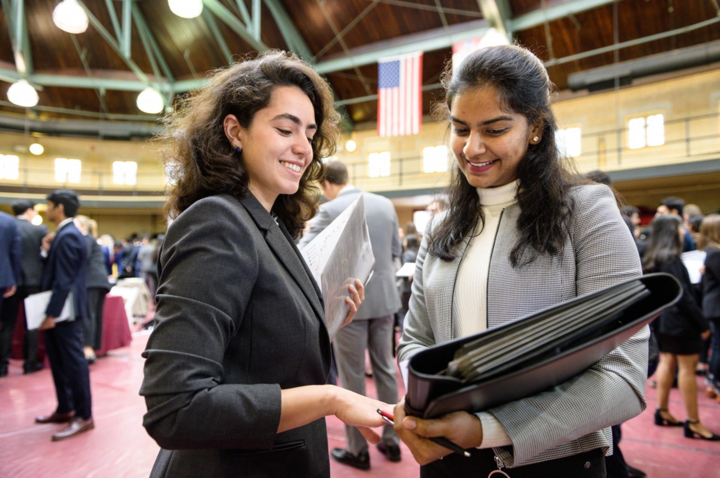 A female recruiter (left) at the internship fair chats with a female student as they go over her resume