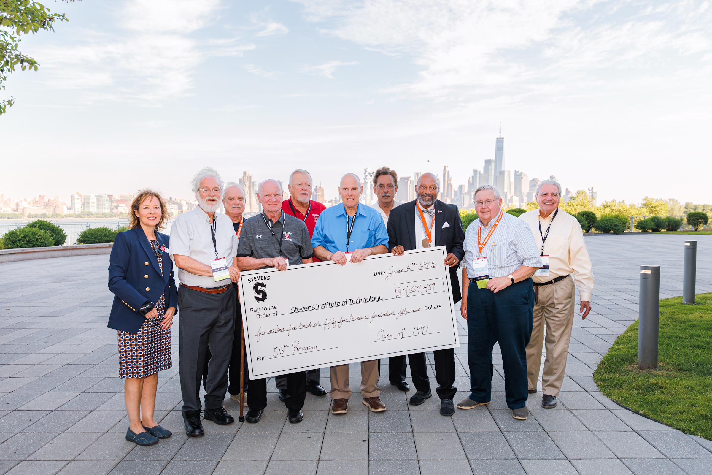 Members of the Class of 1971 pose outdoors with novelty check representing 55th reunion class gift