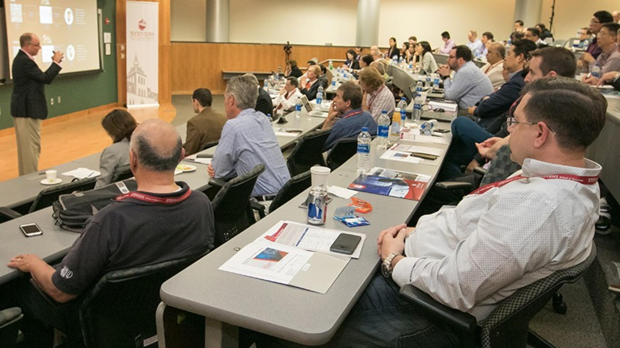 Attendees in a lecture hall watch a presentation by Steve Buckley of IBM about artificial intelligence at the 2018 SAIL Conference