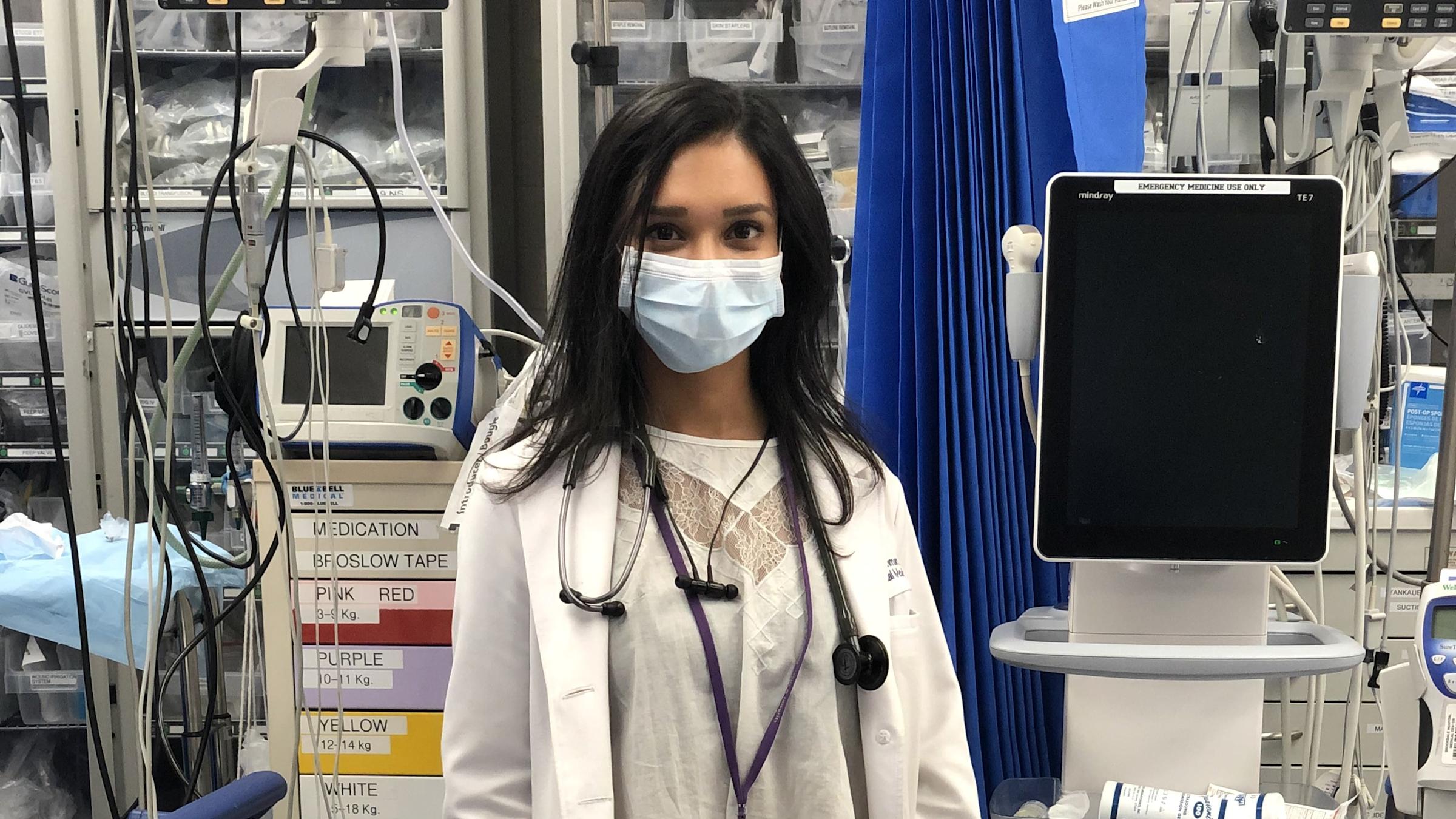 Portrait of resident physician Irene Rahman-Garcia ’12 wearing a mask in a hospital room