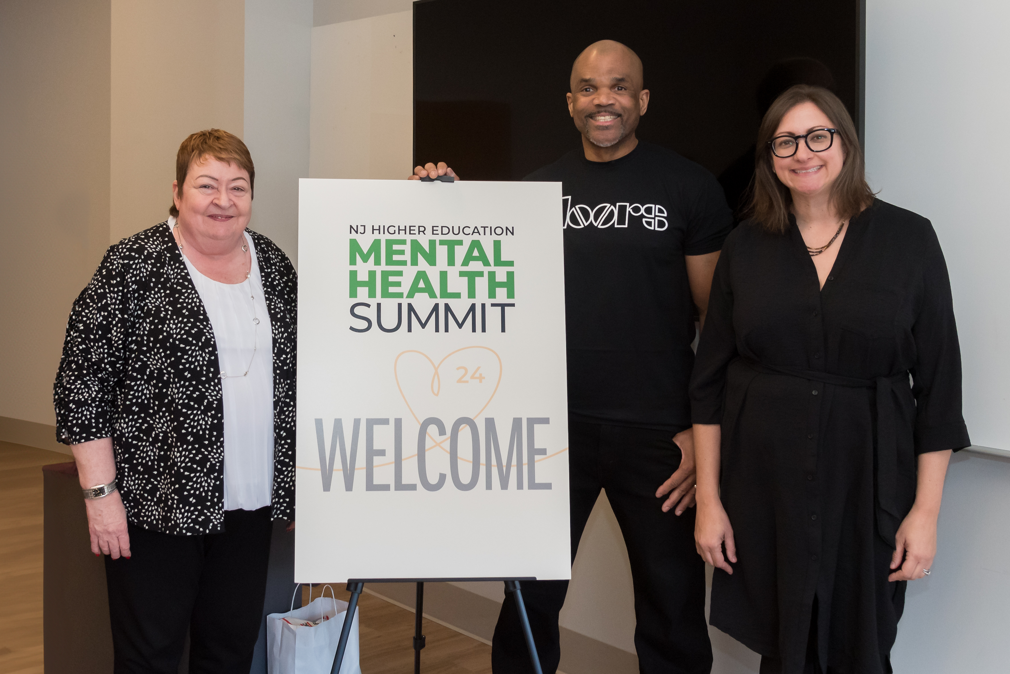 Three people posed in front of the Mental Health Summit sign