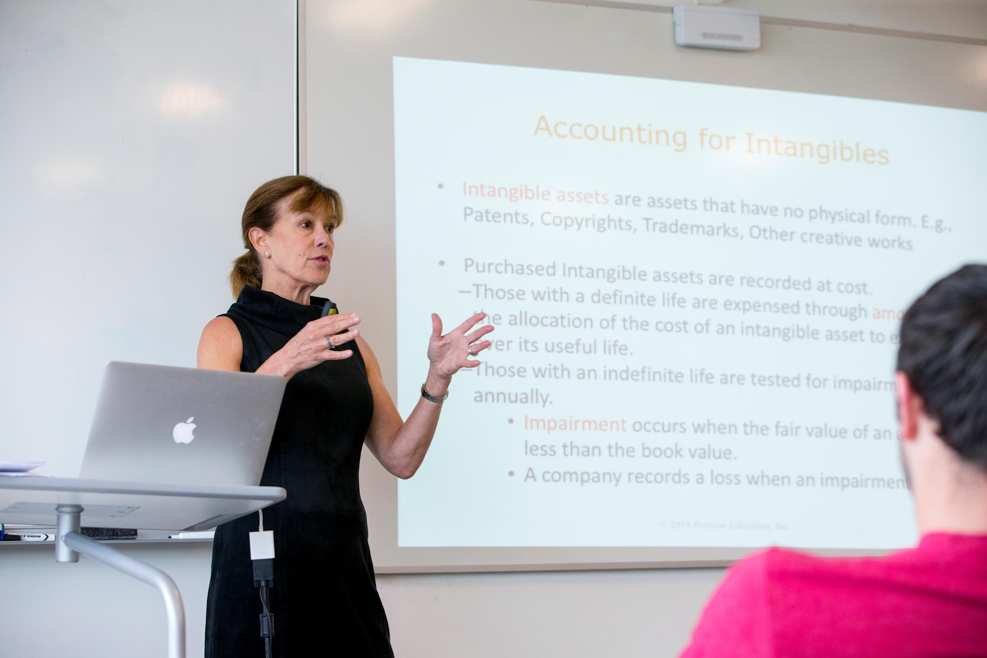 Instructor gestures with hands in front of presentation