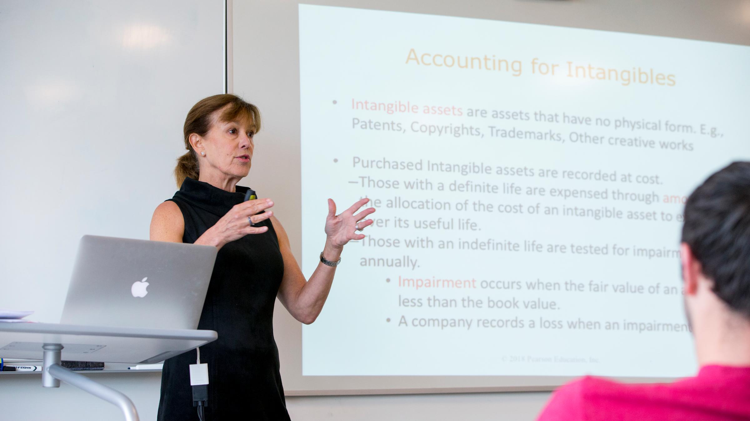 Instructor gestures with hands in front of presentation