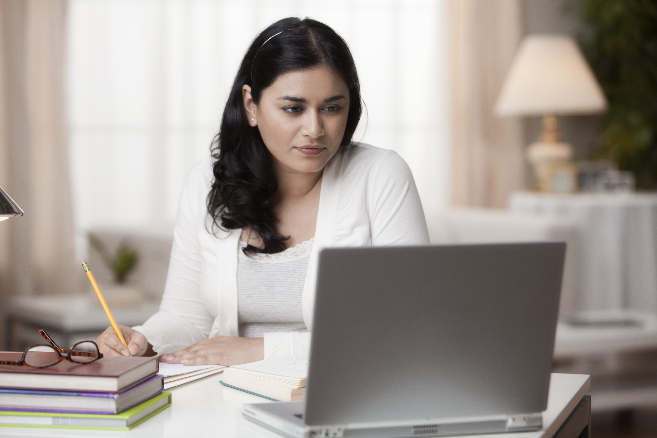 woman taking notes while looking at computer