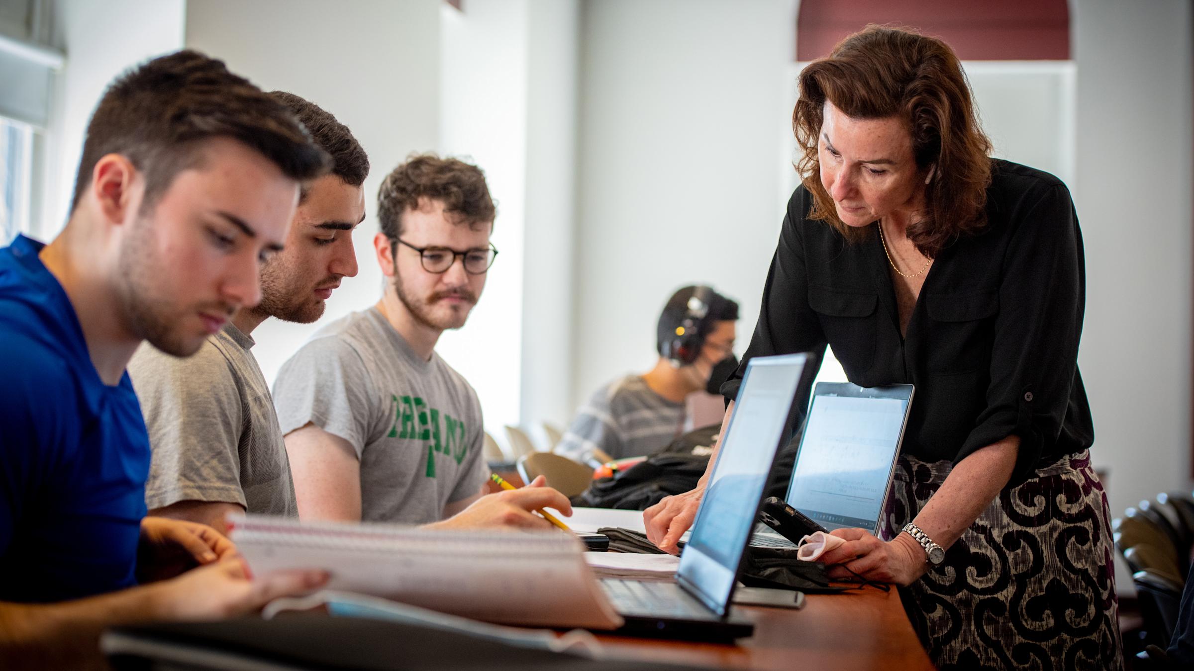 Female professor working with 3 male students in a classroom