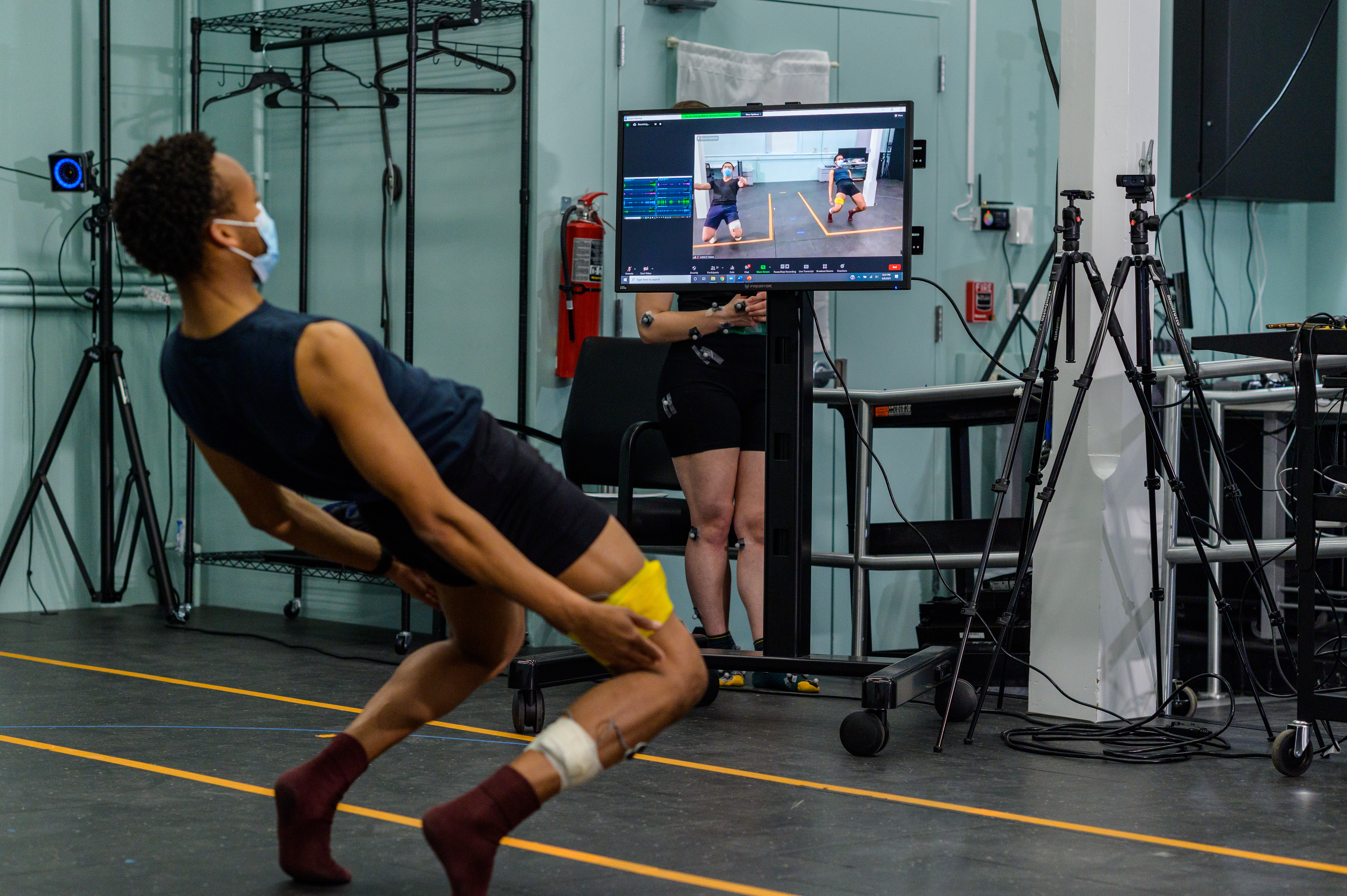 Male student bending backwards while a computer screen mirrors his movement