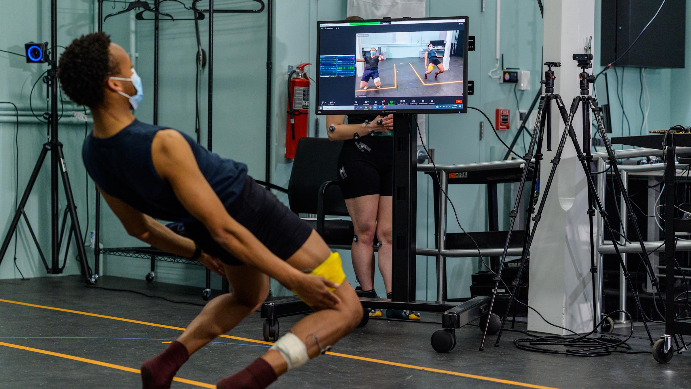 Male student bending backwards while a computer screen mirrors his movement