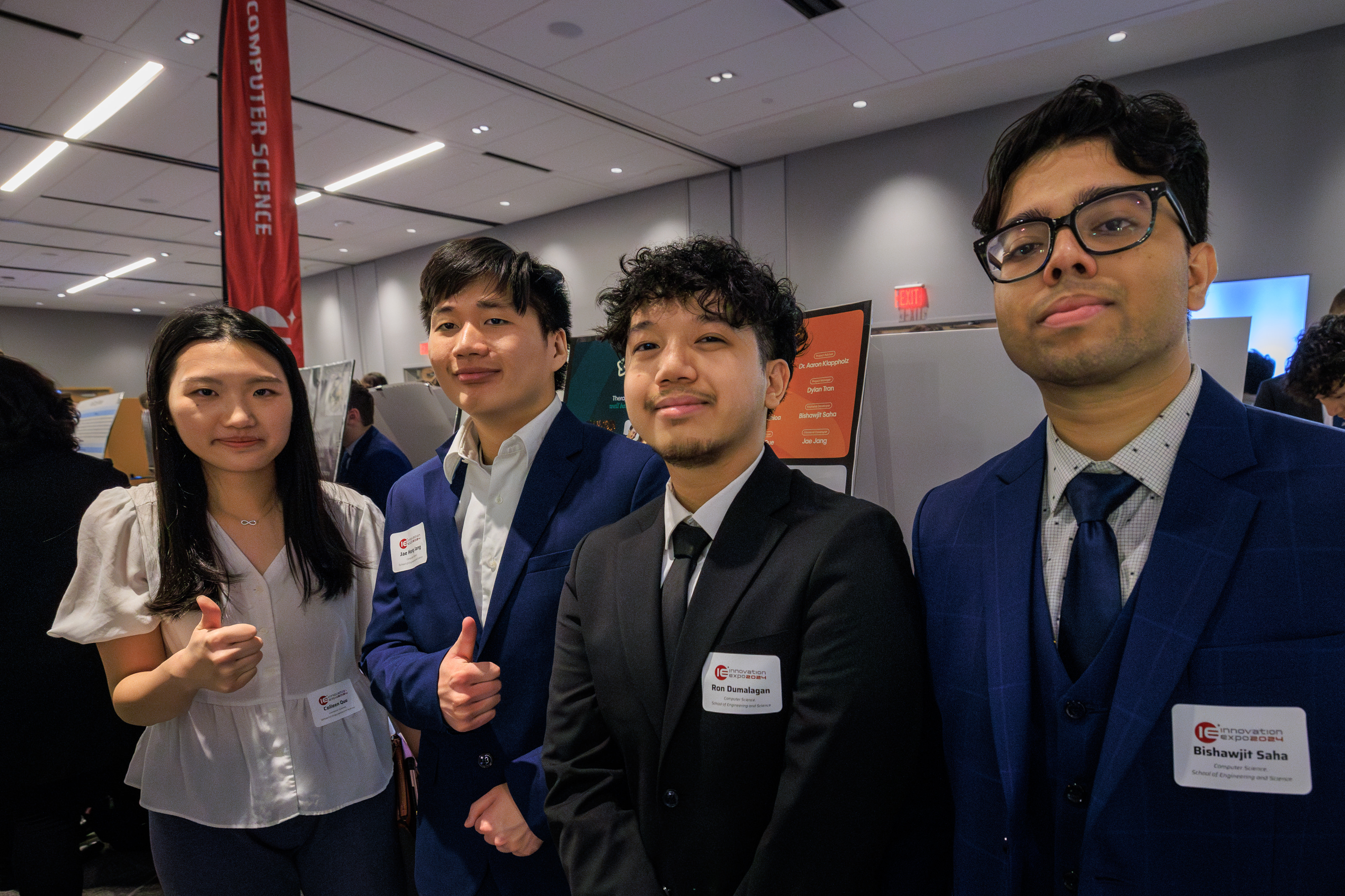 One female and three male students in a conference room with a banner on the left that says computer science
