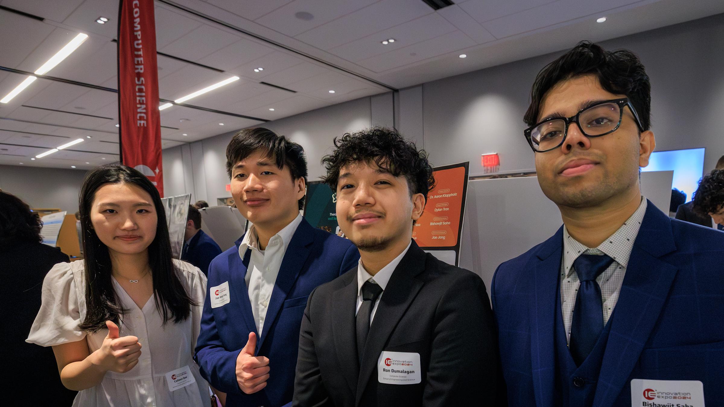One female and three male students in a conference room with a banner on the left that says computer science