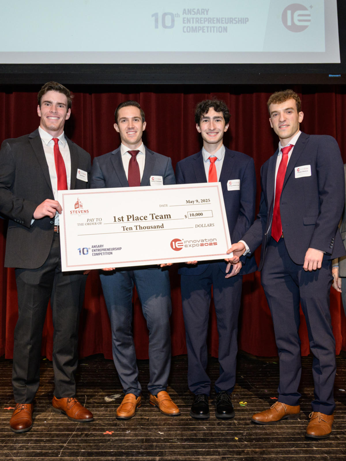 A group of students poses with Stevens's administrators while holding a large check for $10,000.