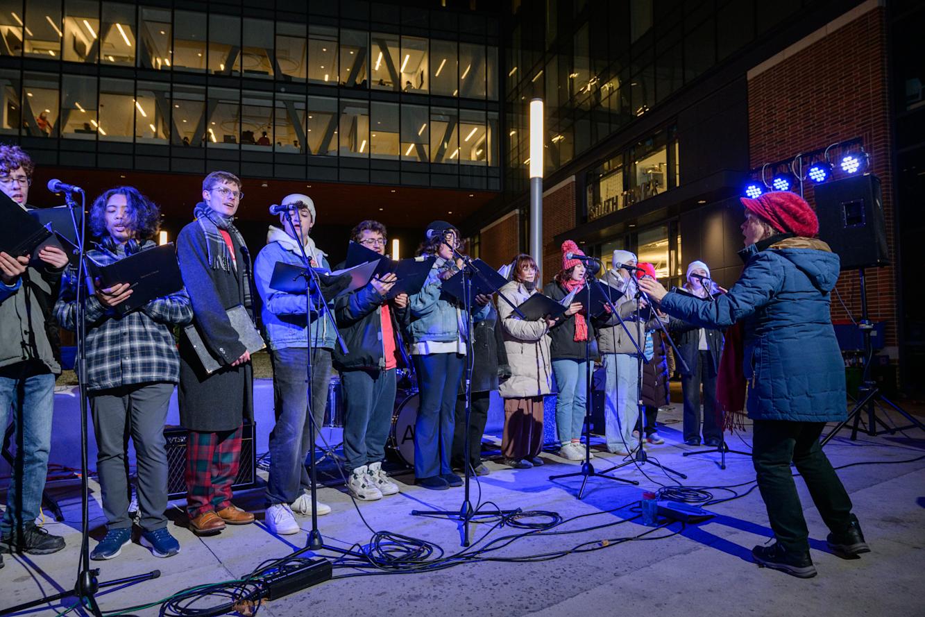 Group of students standing in a line in winter attire singing and holding sheet music