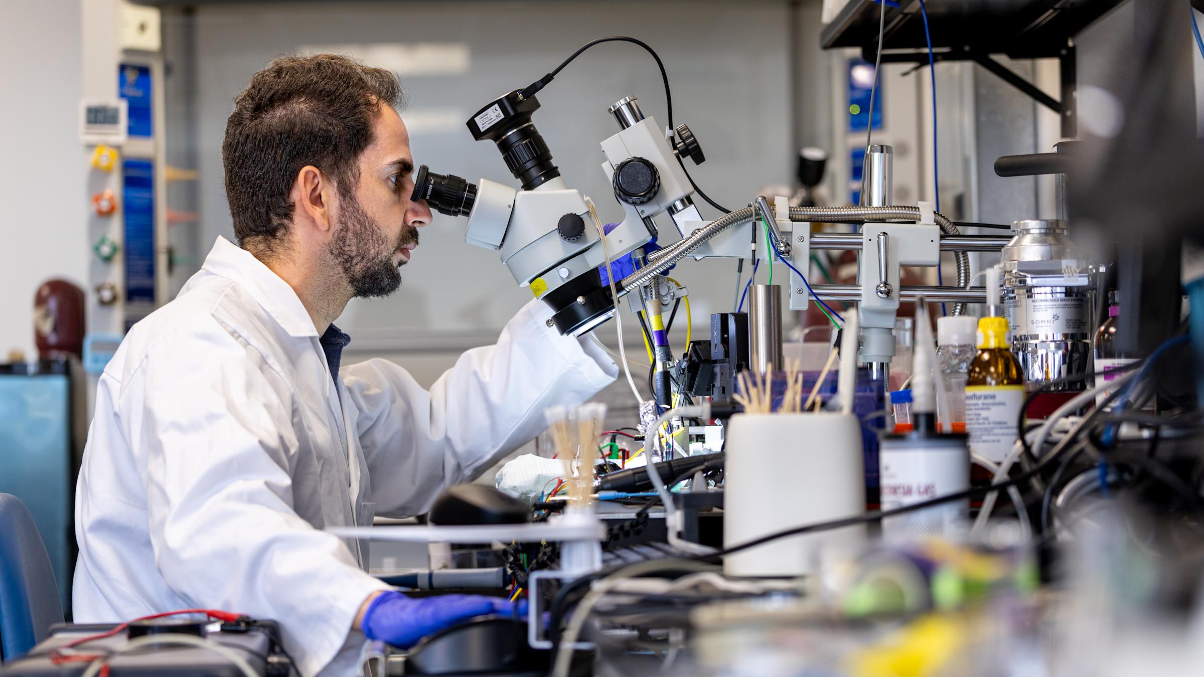 Professor Ilke Uguz working with a microscopic device in a lab.