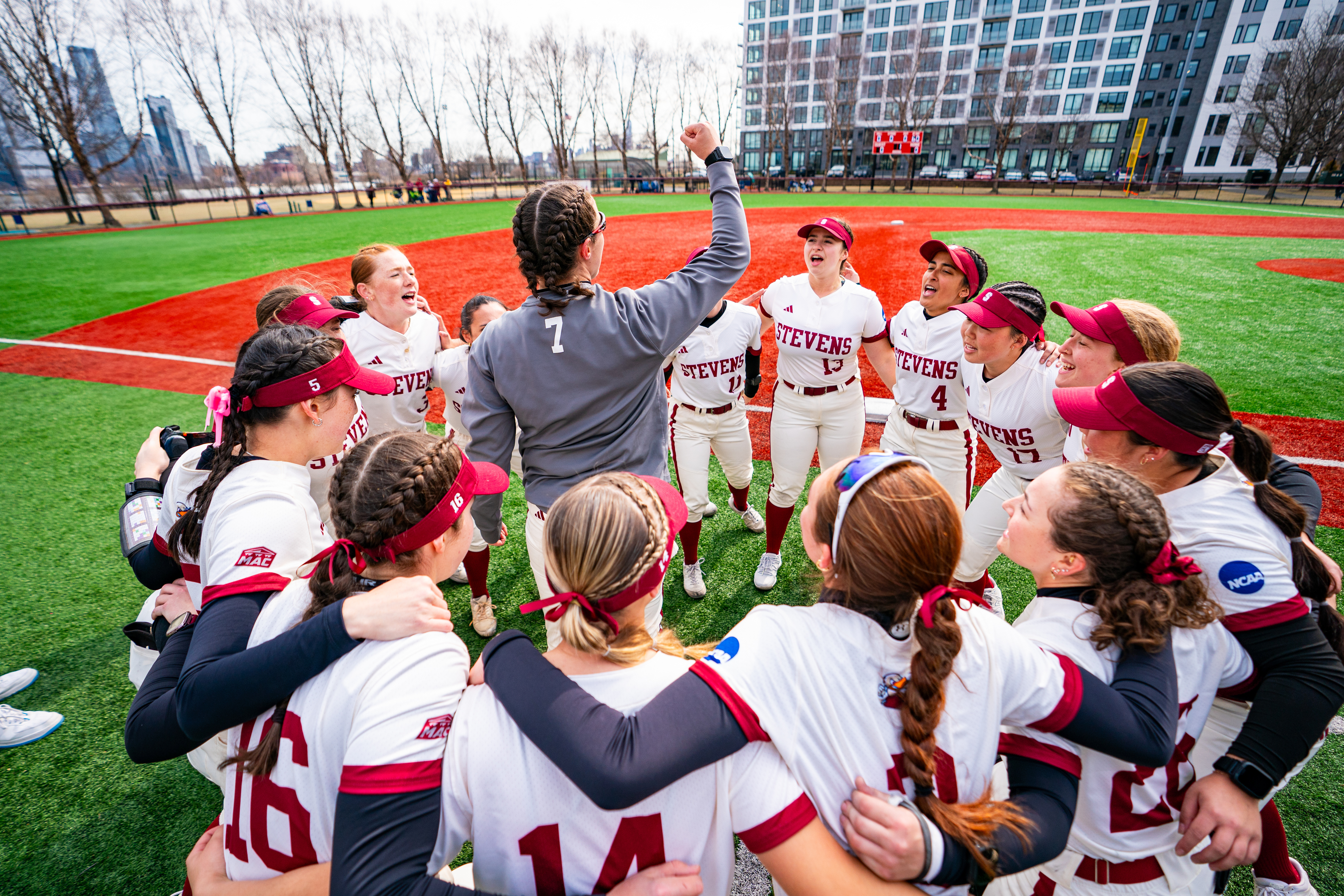 Stevens softball players gather in a huddle on the field together