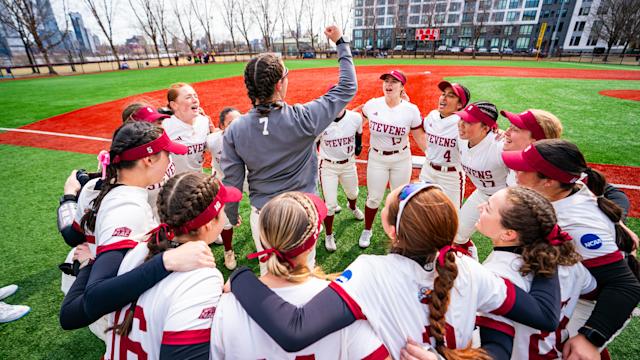 Stevens softball players gather in a huddle on the field together