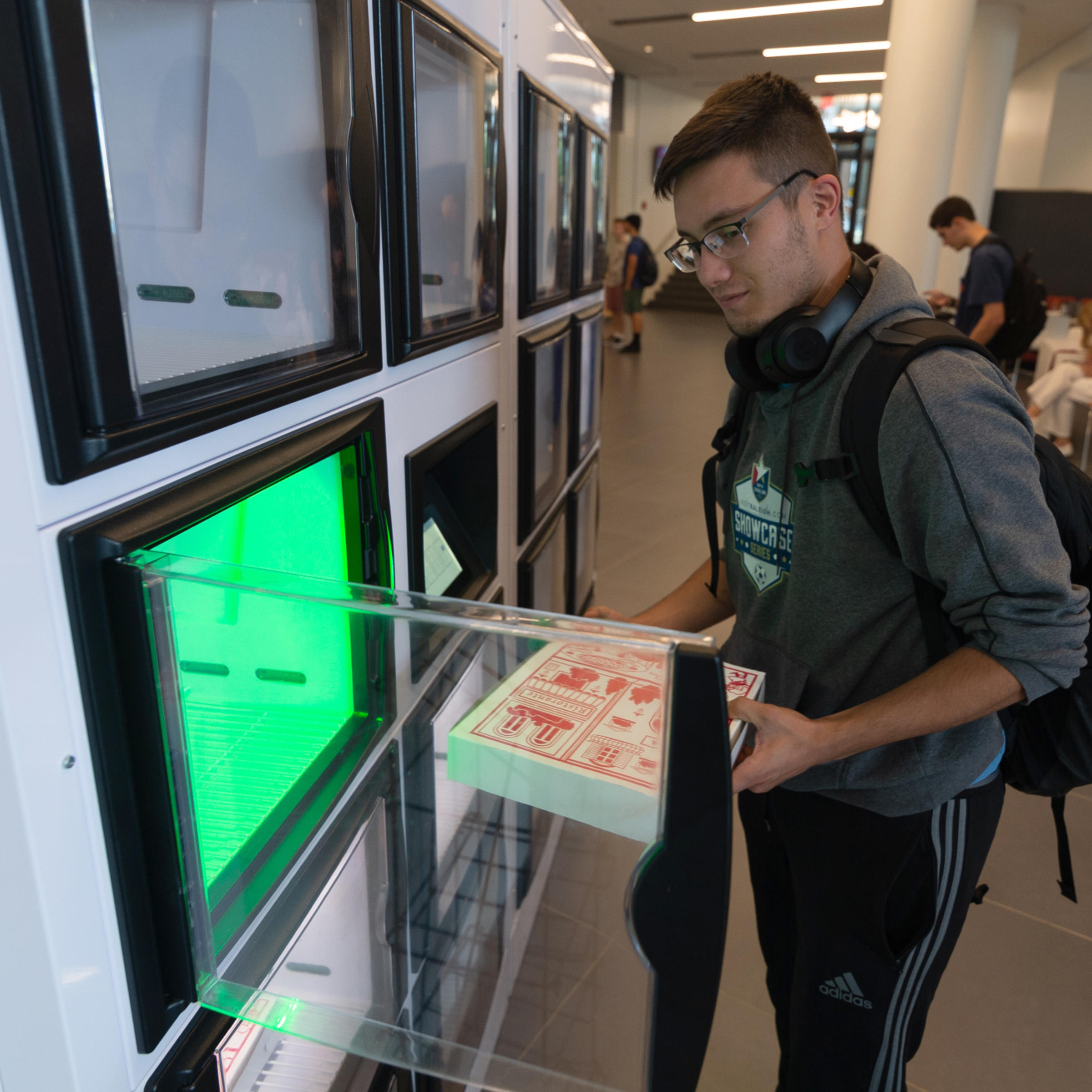 Student pulls box of food from kiosk.